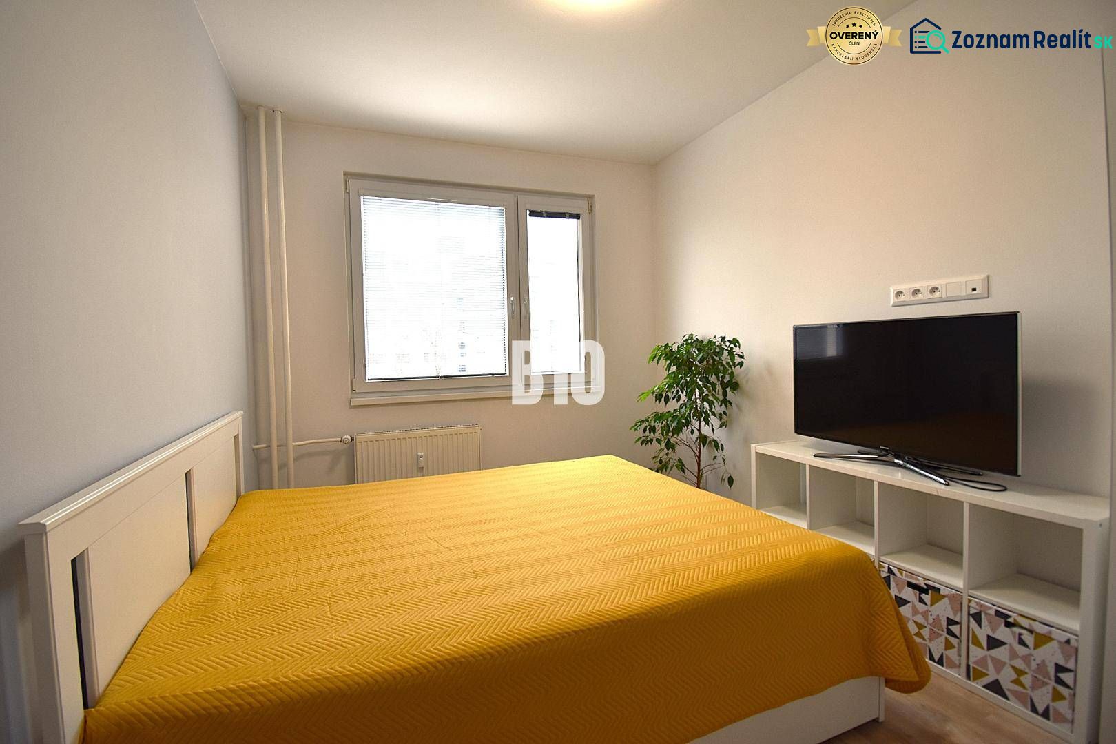 Schlafzimmer in einer 3-Zimmer-Wohnung mit Bett, Fernseher und Holzboden.