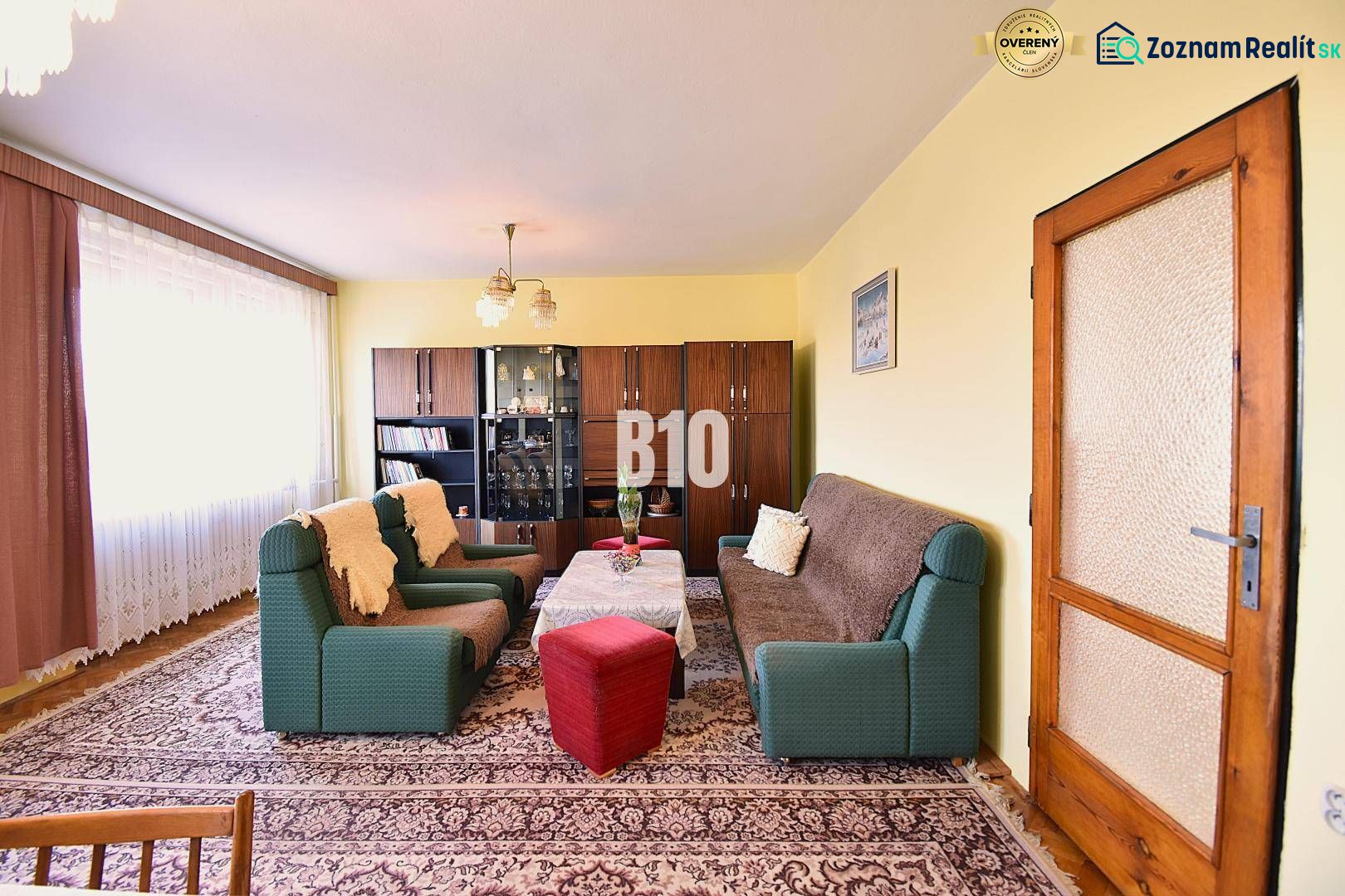 Wohnzimmer in einem Einfamilienhaus mit Sofas, Sesseln, Vitrine und Teppich.