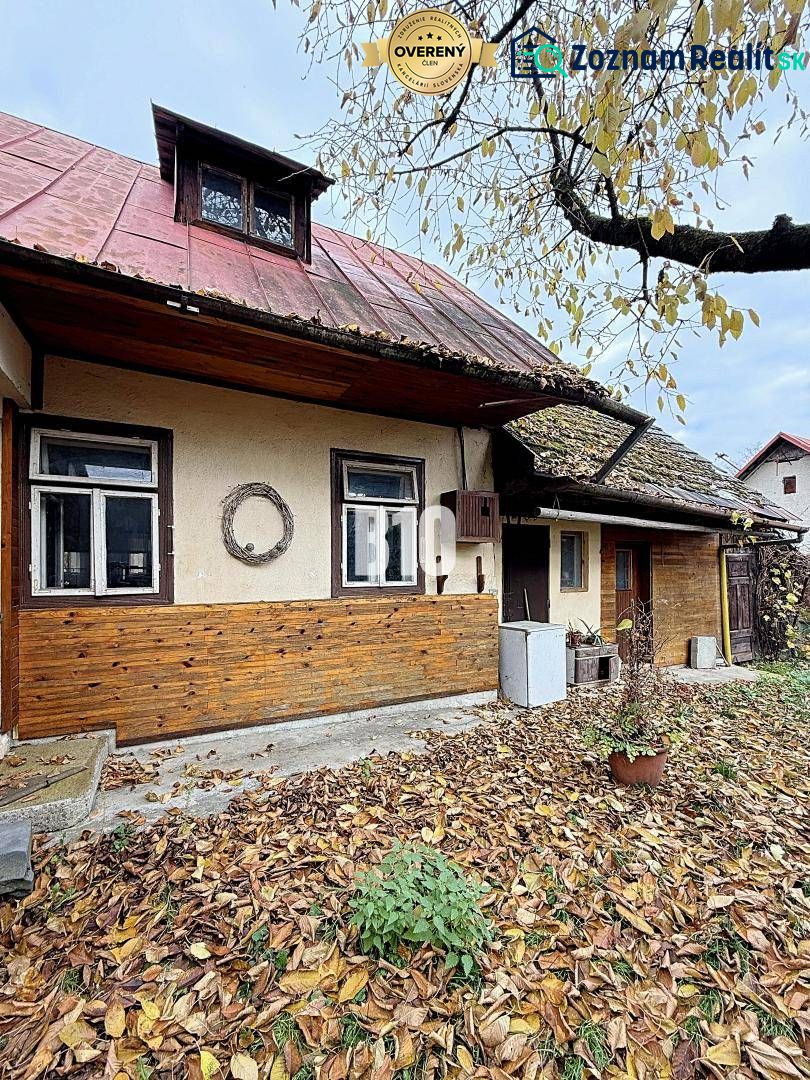 Ein Einfamilienhaus in Kotešová mit alter Holzverkleidung und fallendem Laub im Garten.