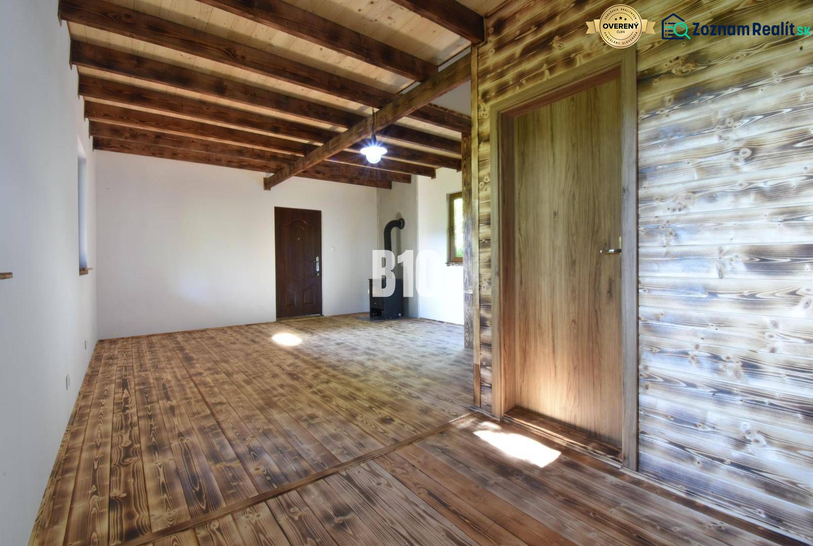 Interieur einer Hütte mit Holzbalken, Holzboden und einem Ofen zum Heizen.