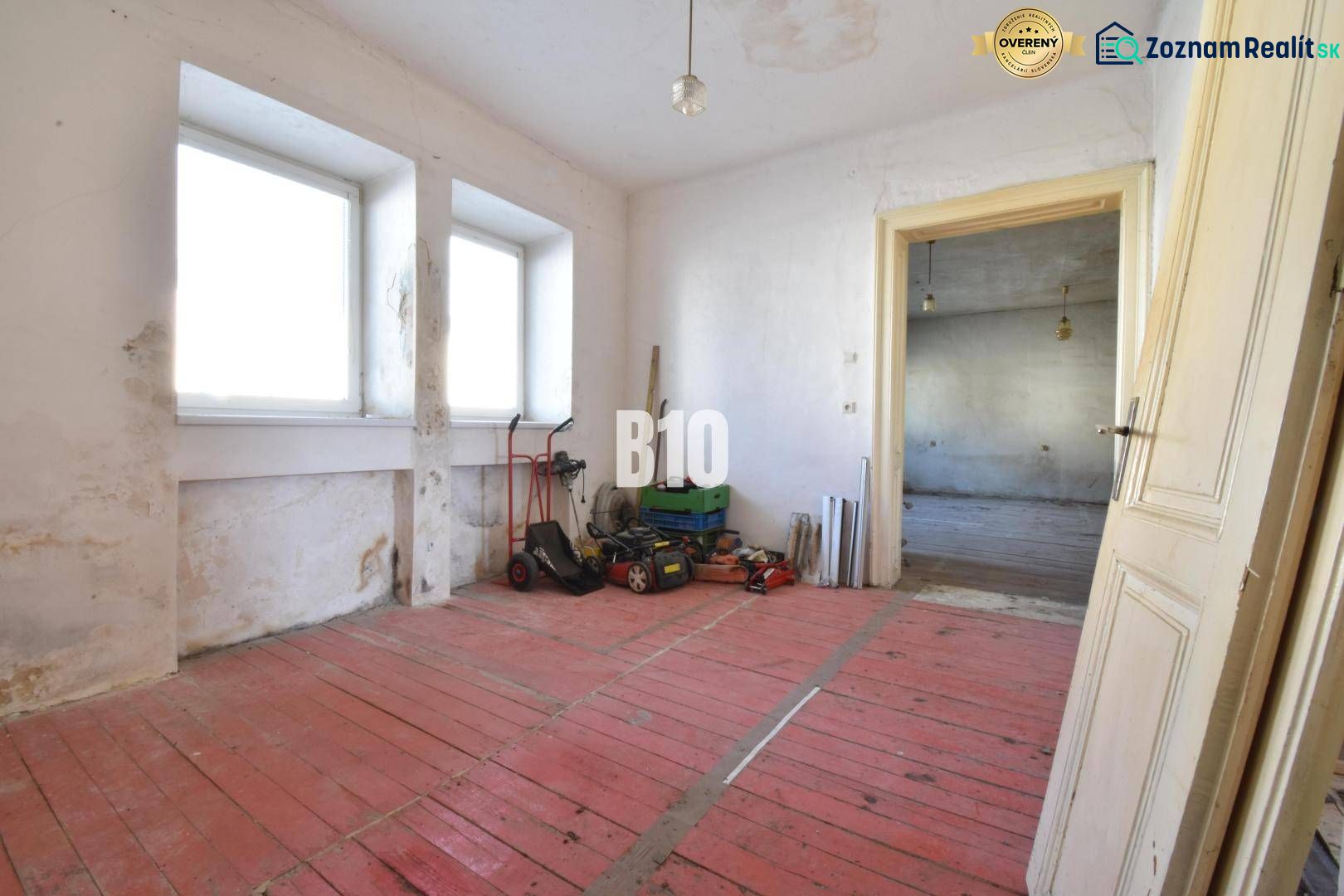 Ein Zimmer in einem Einfamilienhaus mit rotem Boden und Fenstern, Bytča.