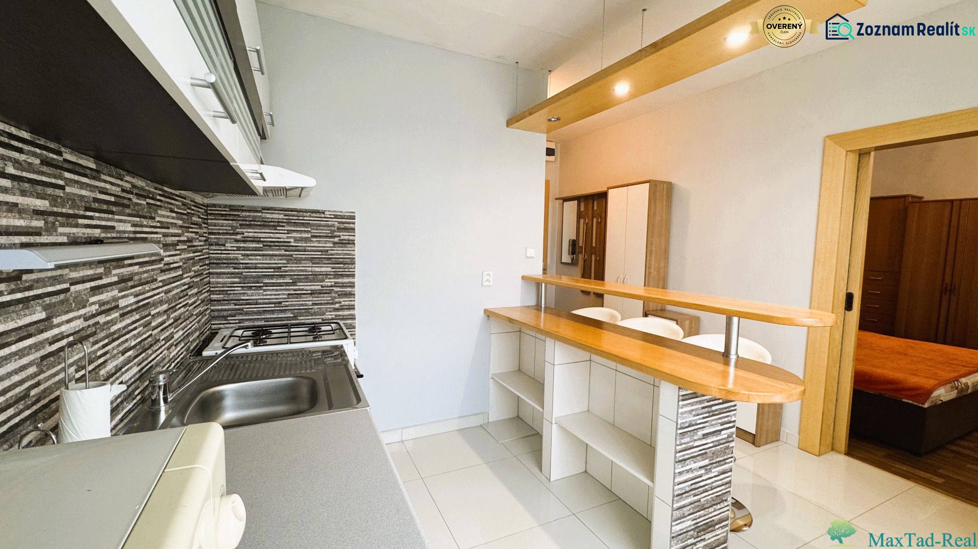 Küche in einer Einzimmerwohnung mit Bartresen und Boden in Holzoptik.
