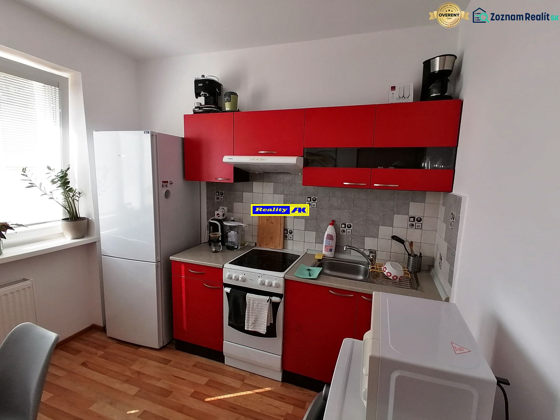 Küche mit roten Schränken und Holzdekorboden in einer Einzimmerwohnung.