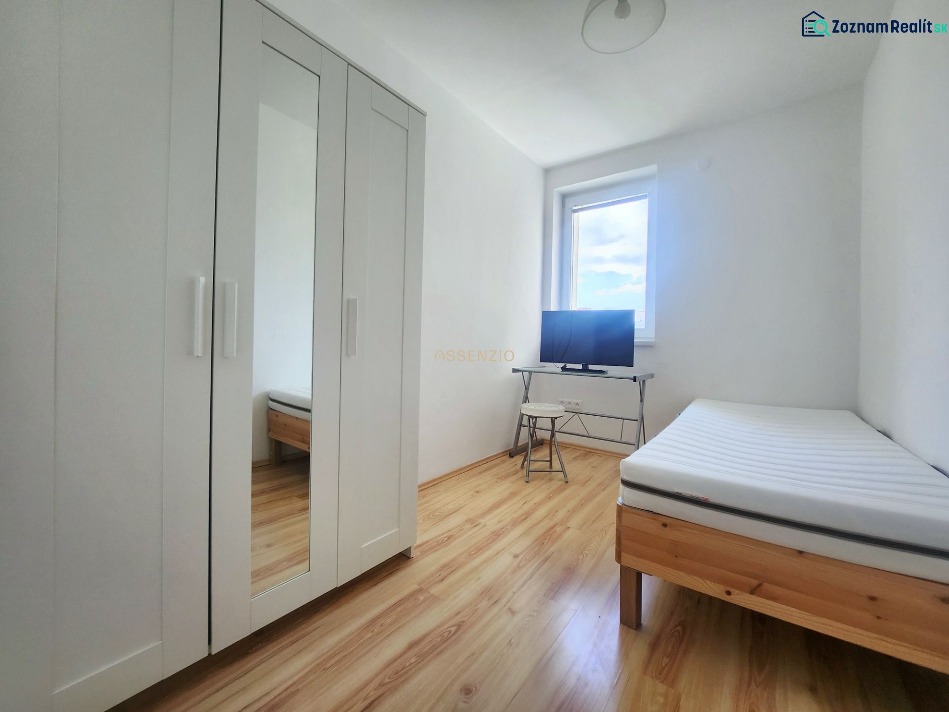 Helles Zimmer mit Bett, weißem Schrank und Fernseher, 3-Zimmer-Wohnung, Boden mit Holzdekor.