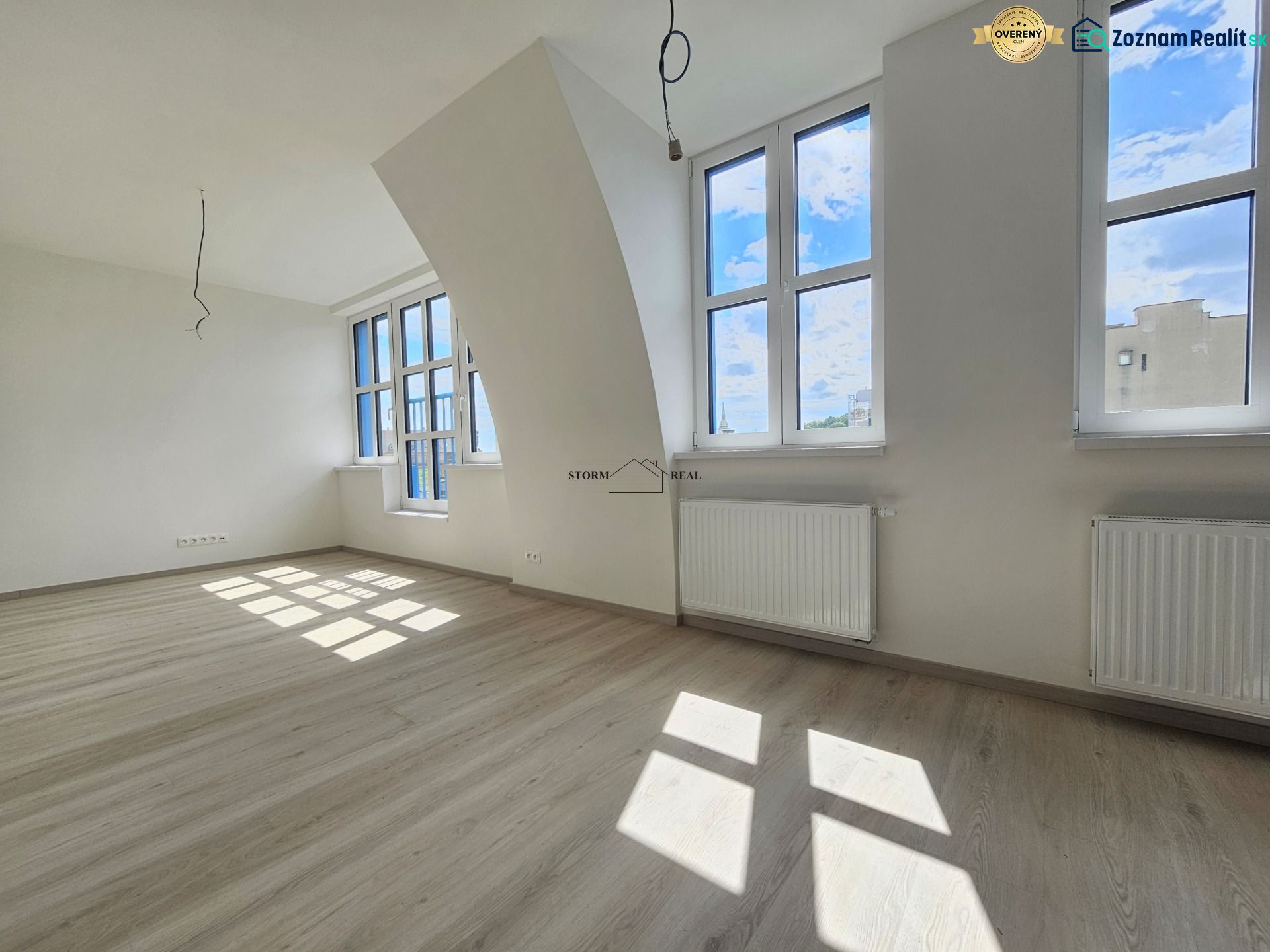 Helle 1-Zimmer-Wohnung mit Fenstern und Boden in Holzoptik.