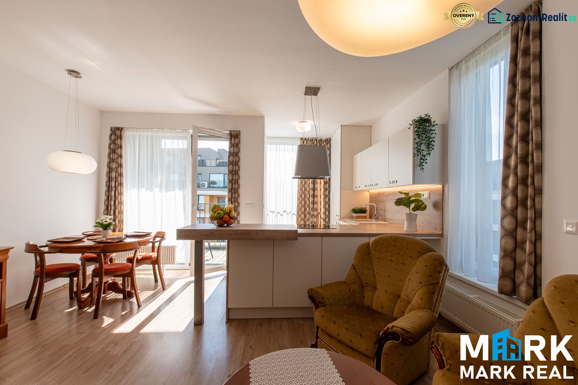 Wohnzimmer verbunden mit Küche, Esstisch, Boden mit Holzdekor, helle Vorhänge.