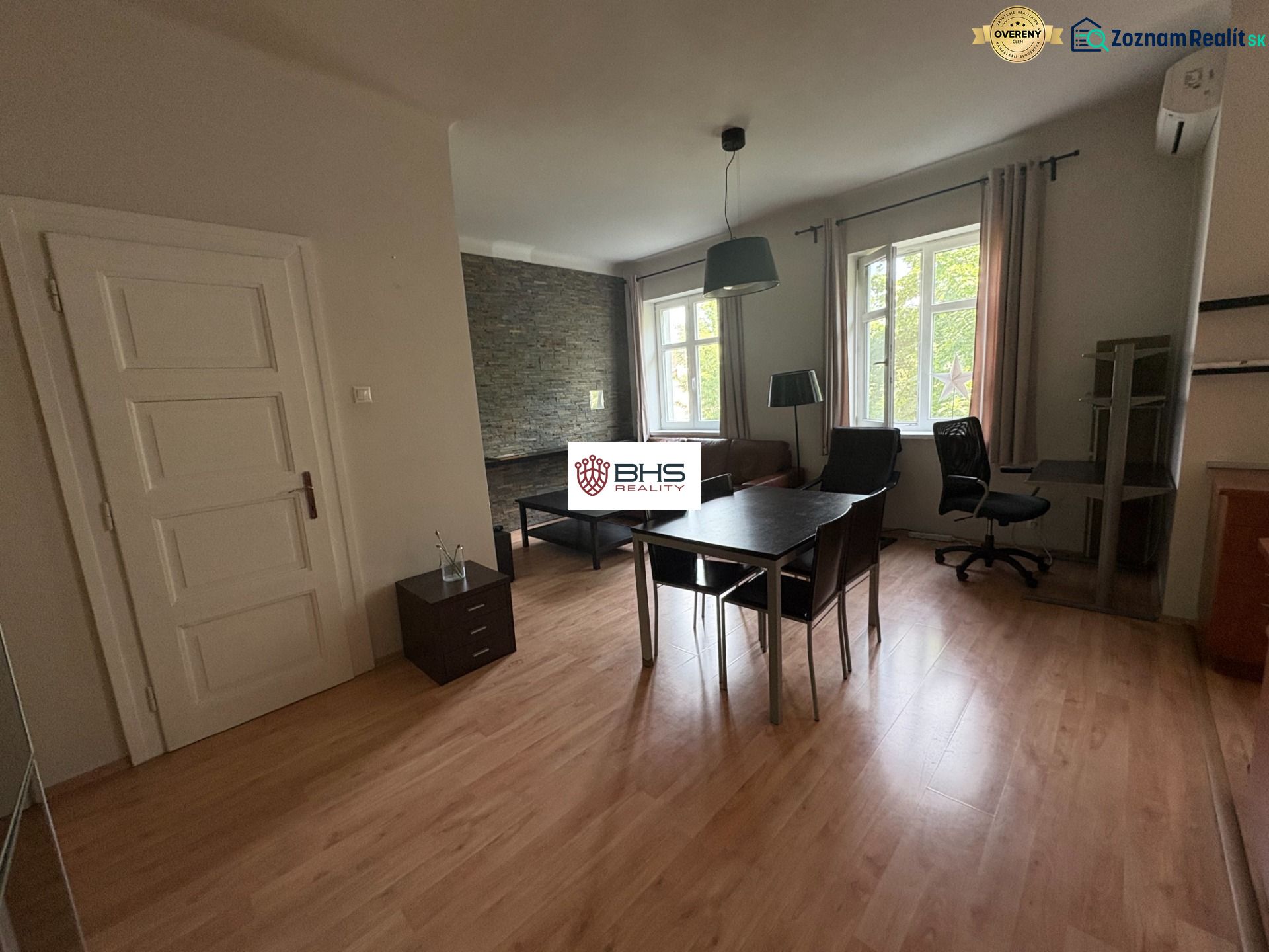 Innenraum einer 2-Zimmer-Wohnung mit Holzboden, Tisch und Stuhl.