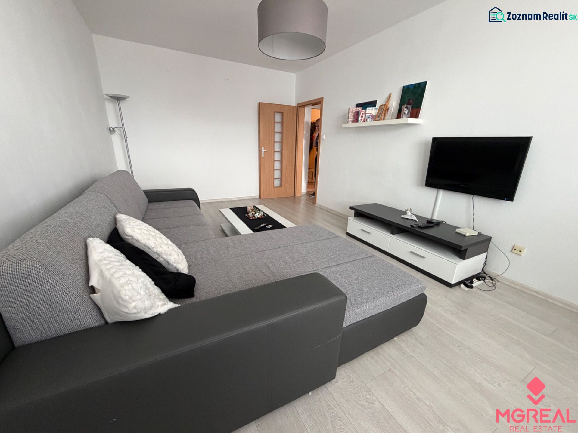 Wohnzimmer in einer Zweizimmerwohnung mit Holzboden und Ecksofa.