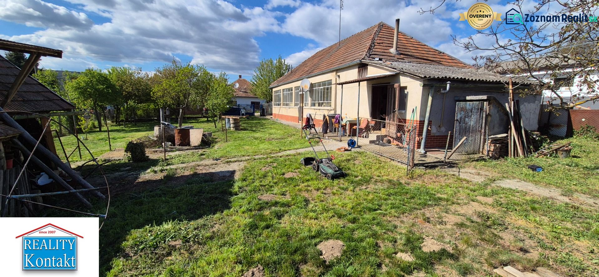 Žiadna Dedinka: Einfamilienhaus mit Garten und Anbau, mit einem Rasenmäher auf dem Rasen.