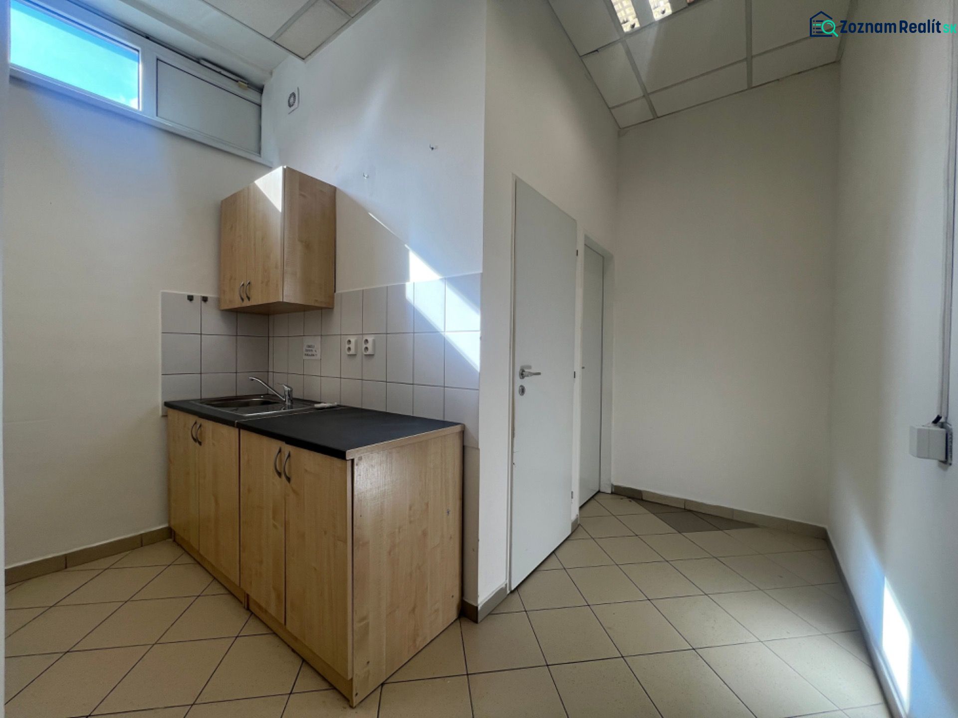 Kleine Küche mit Spüle und Schränken in Geschäftsräumen.