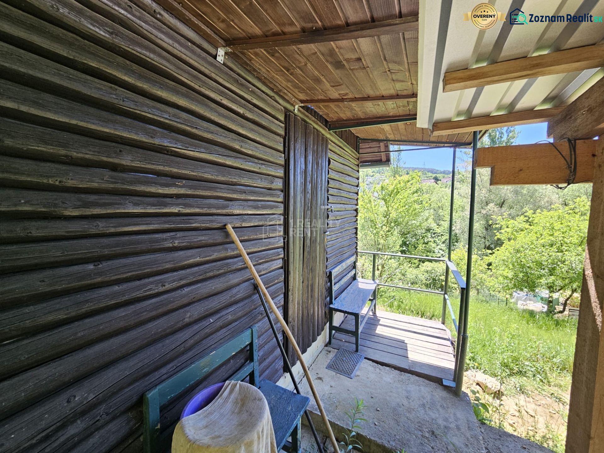 Eine Hütte in Budatín mit Holzverkleidung, Terrasse und Blick auf den grünen Garten.