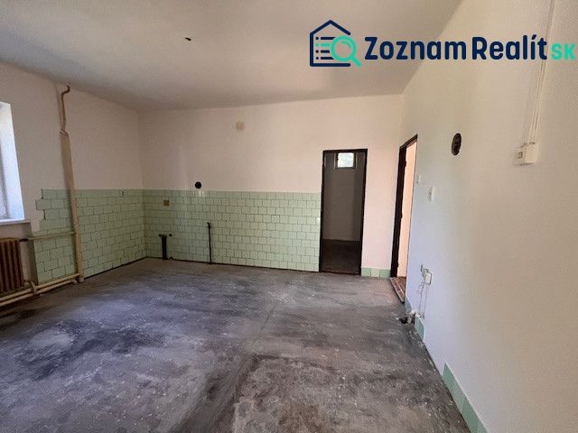 Ein Zimmer in einem Einfamilienhaus mit unfertigem Boden und grünen Fliesen.