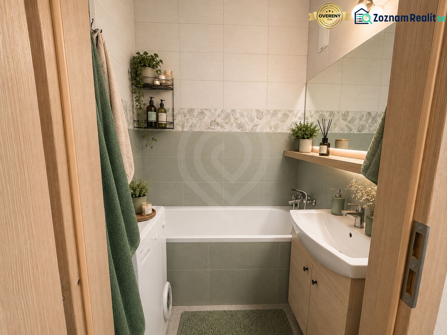 Ein Badezimmer in einer 3-Zimmer-Wohnung mit Badewanne, Waschmaschine und Dekorationen in natürlichen Tönen.
