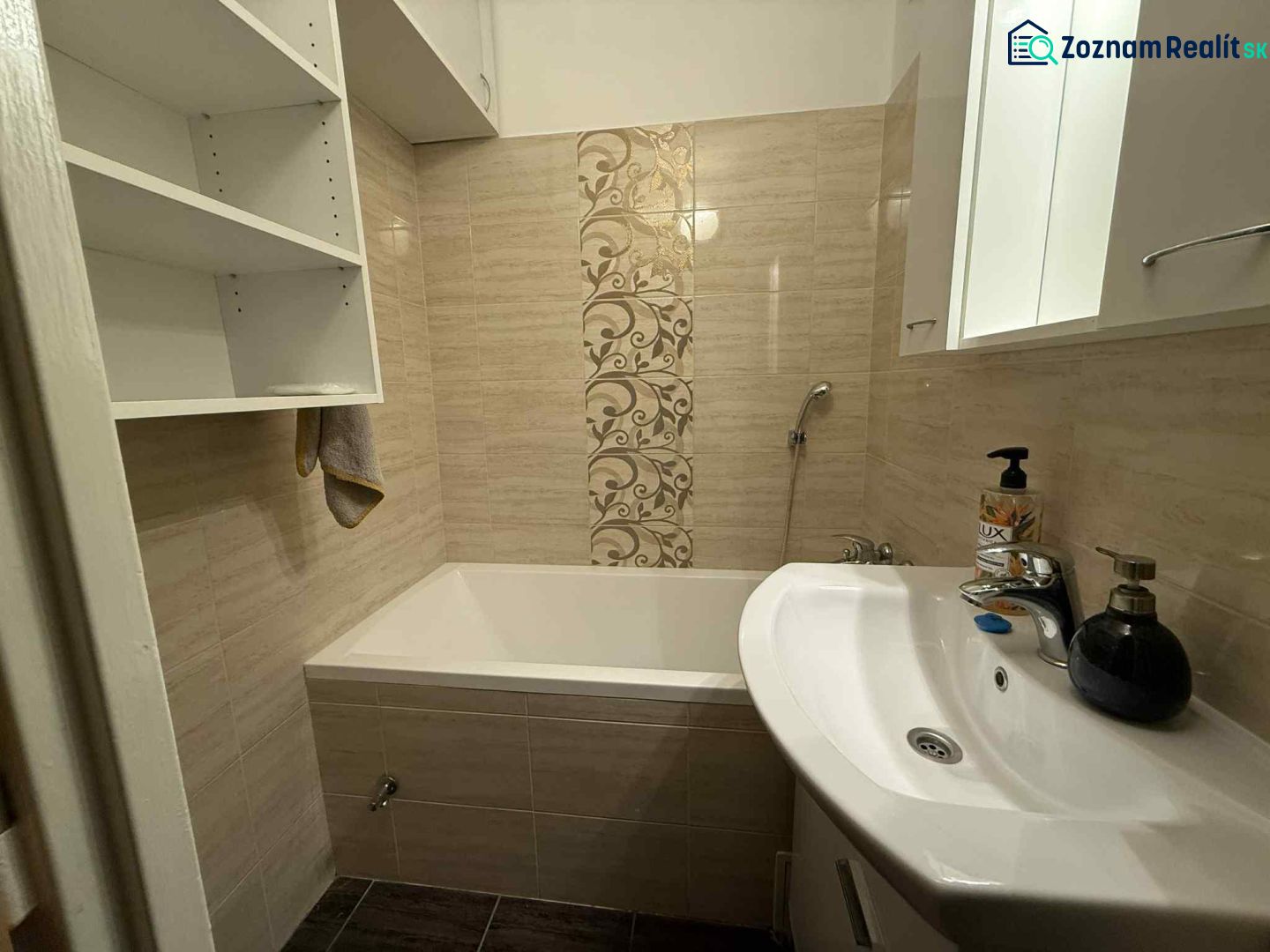 Badezimmer mit Badewanne in einer 4-Zimmer-Wohnung, mit Ablagefächern und dekorativen Fliesen.