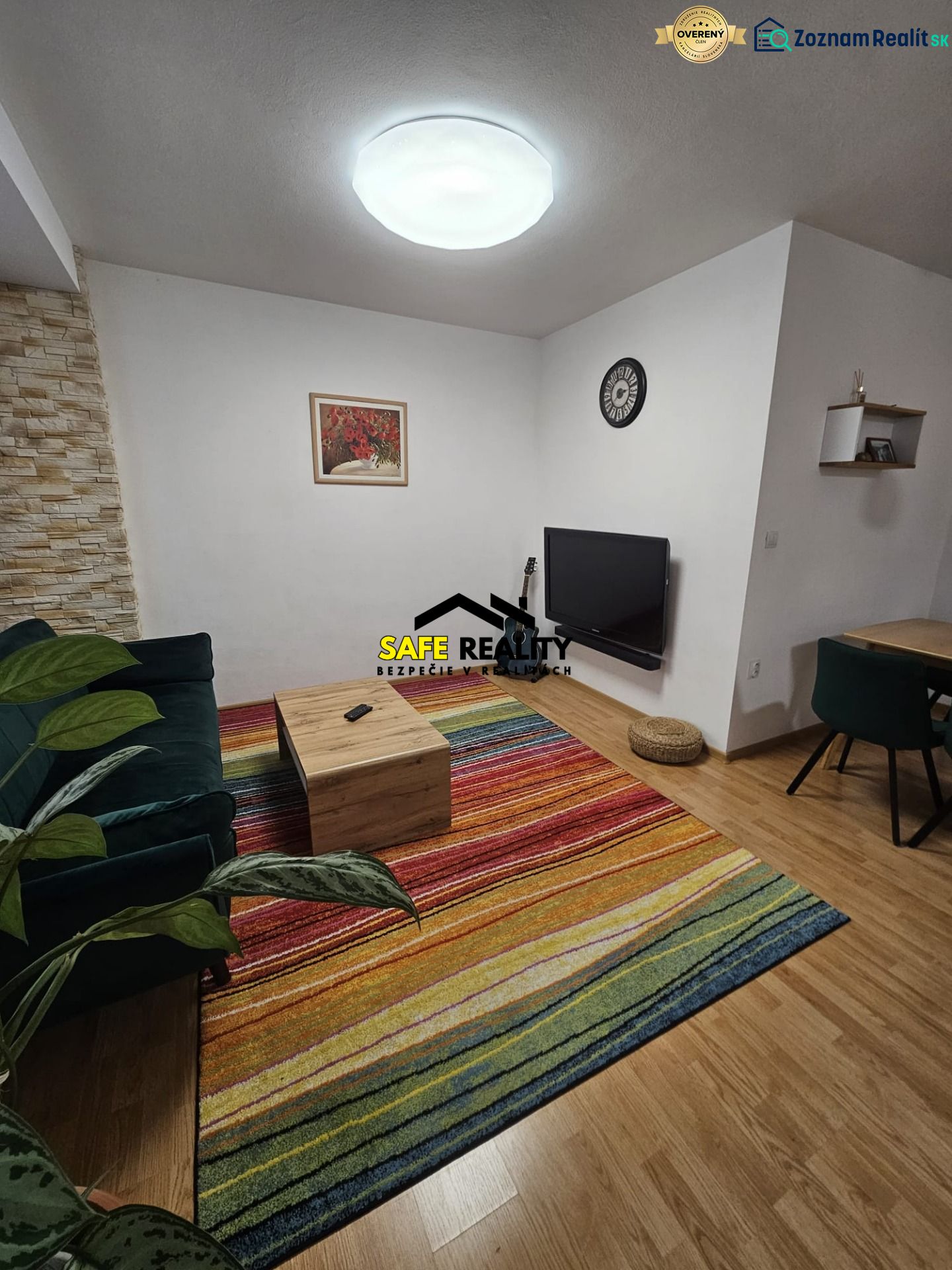 Wohnzimmer in einer 3-Zimmer-Wohnung mit einem bunten Teppich und einem Boden in Holzoptik.
