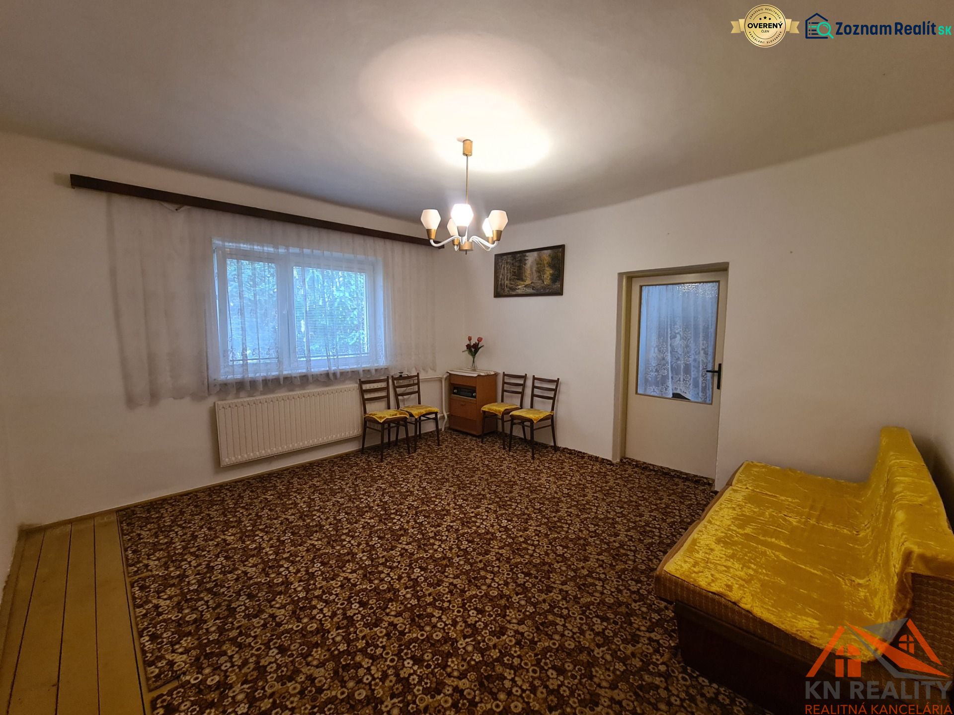 Wohnzimmer in einem Einfamilienhaus mit Teppich und gelbem Sofa.