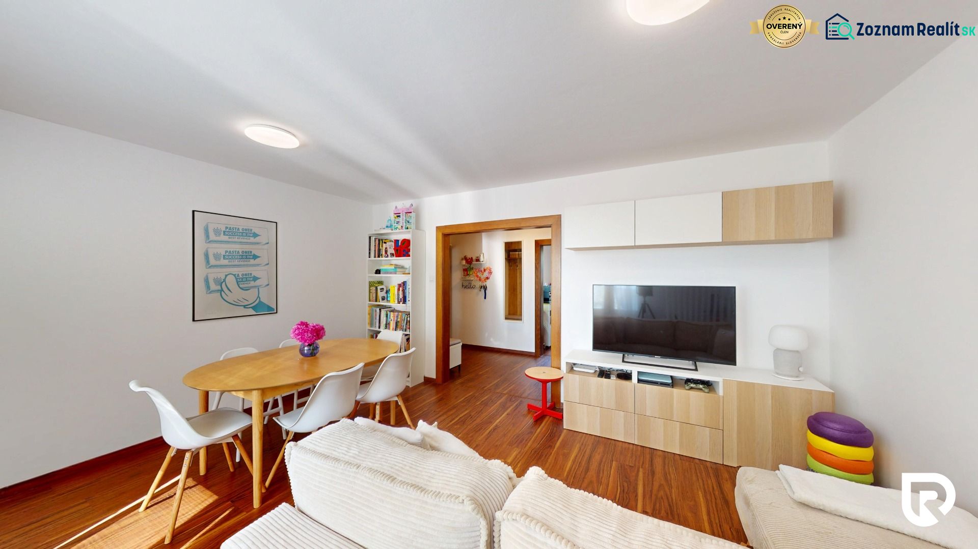 Wohnzimmer mit Holzdekor, Esstisch, Bücherregal und TV-Schrank.