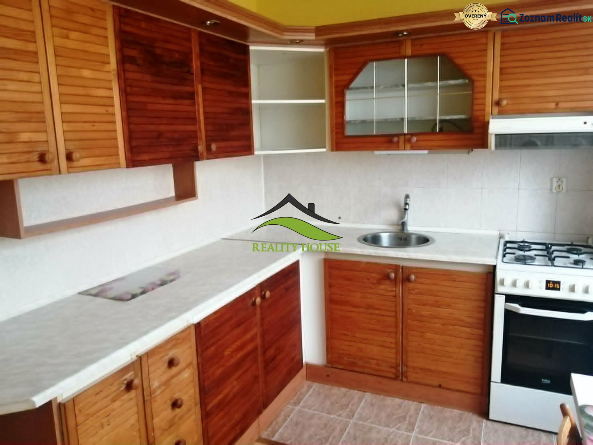 Küche in einer 3-Zimmer-Wohnung mit Holzschränken und weißer Arbeitsplatte.