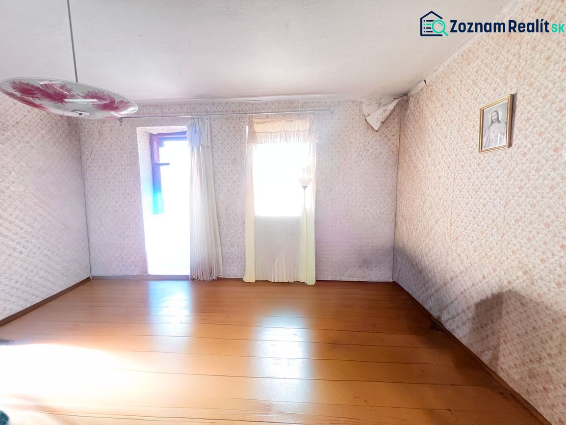 Ein Zimmer in einem Einfamilienhaus mit einem Holzboden, einem Blumenleuchter und einem Bild an der Wand.