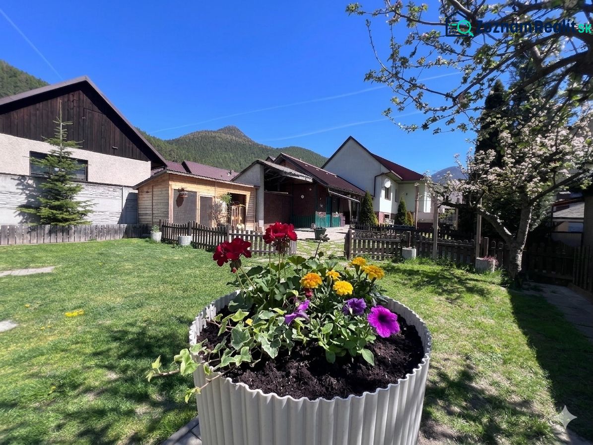Ein Einfamilienhaus in Švošov mit bunten Blumen und einem grünen Rasen im Garten.