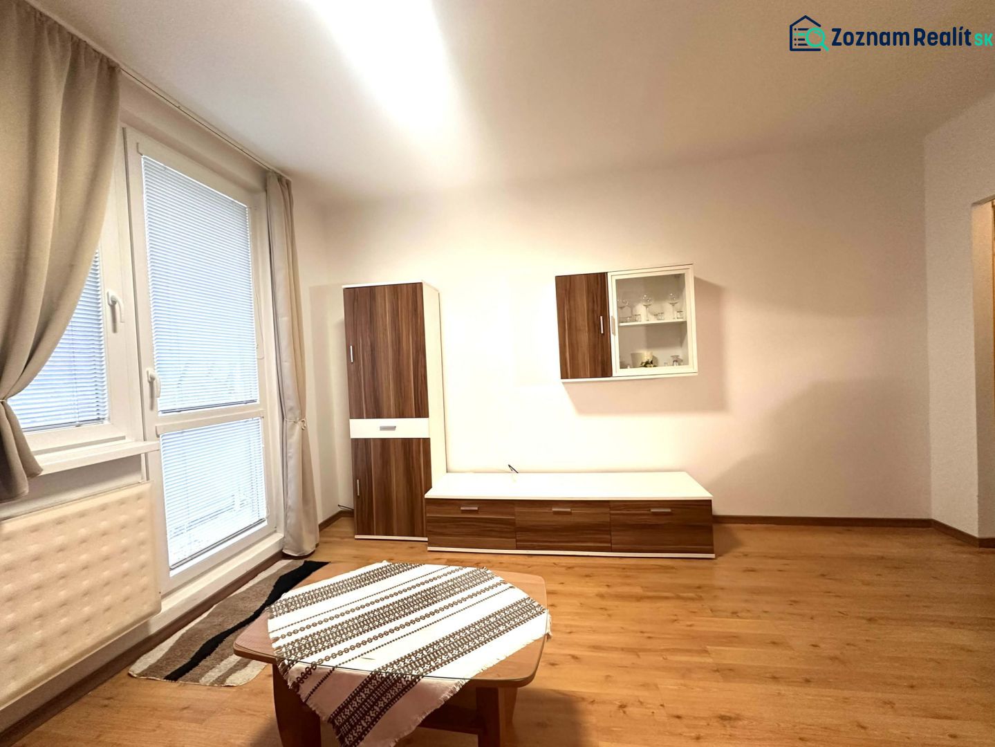 Ferienwohnung mit Holzboden, Möbeln und großem Fenster.