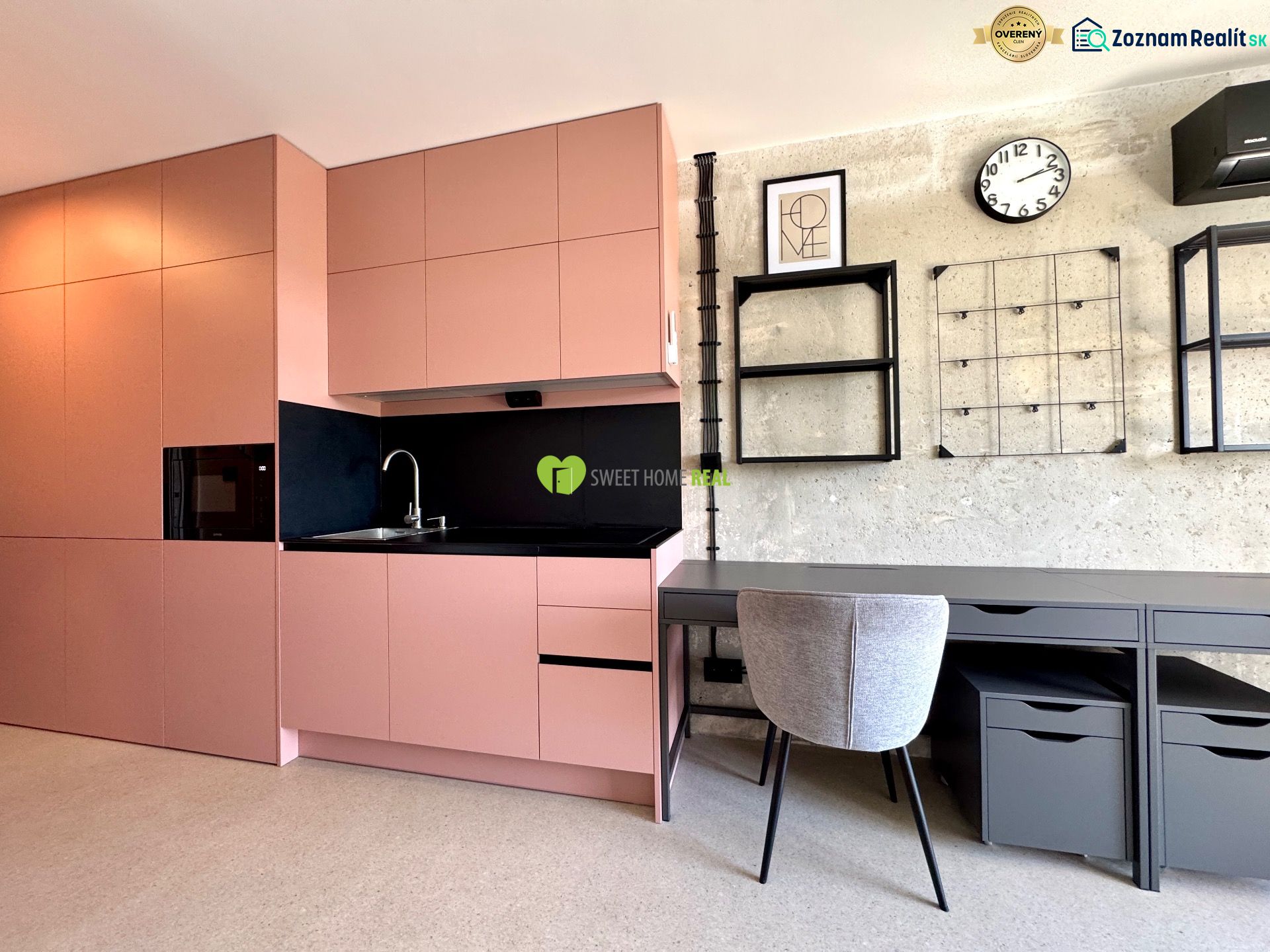 Küche und Arbeitsecke in einem Studio-Apartment mit modernen Regalen und einer Uhr an der Wand.