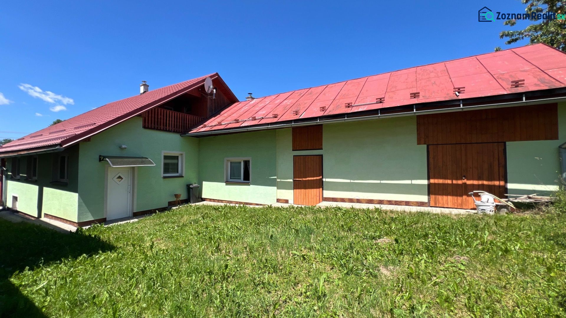 Ein Einfamilienhaus in Polomka mit bunten Fassaden und einem roten Dach vor einem blauen Himmel.