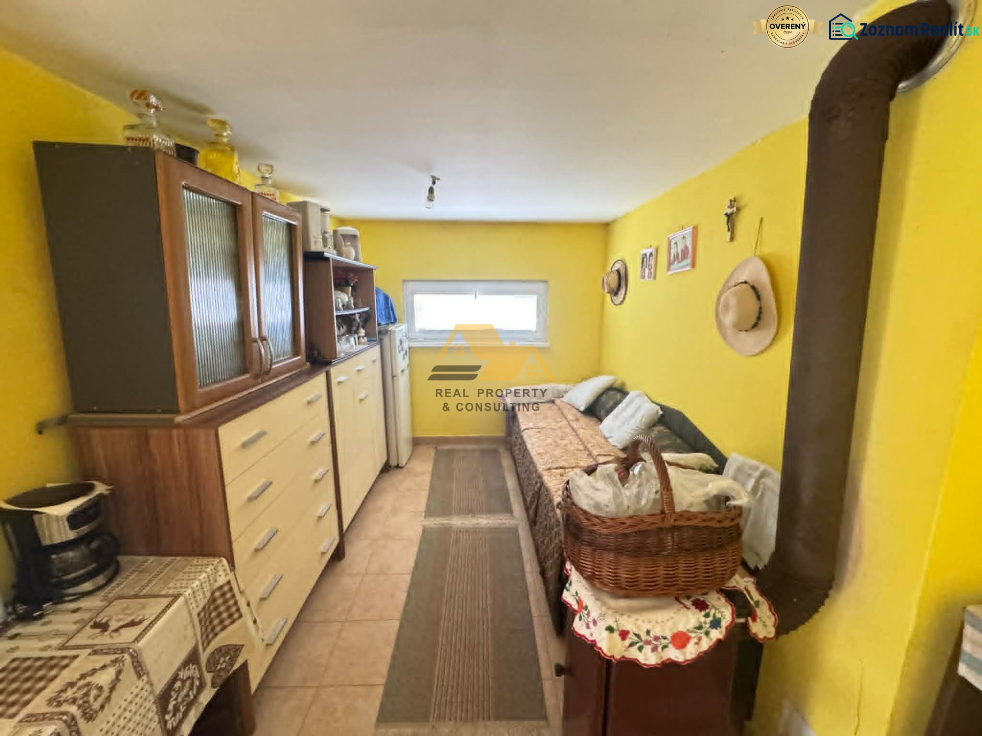 Das Innere der Hütte mit einem Holzschrank und einem Teppich auf dem Boden in Holzoptik.