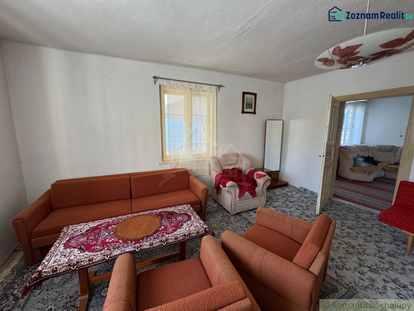 Wohnzimmer in einem Einfamilienhaus mit einem orangefarbenen Sofa und einem gemusterten Teppich.