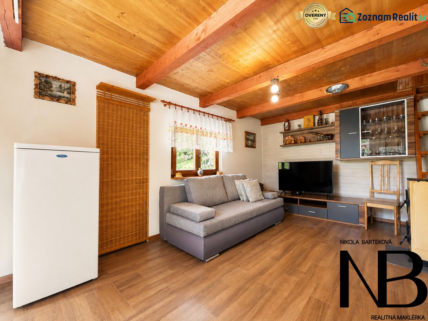 Wohnzimmer der Hütte mit Holzboden, bequeme Couch, Fernseher und Schränke.