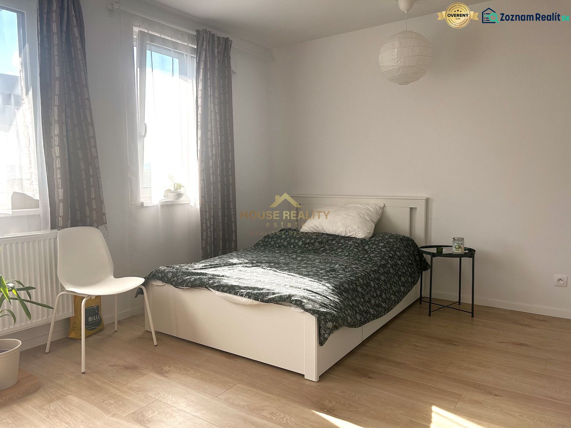 Helles Zimmer in einer Einzimmerwohnung mit Bett und Holzboden.