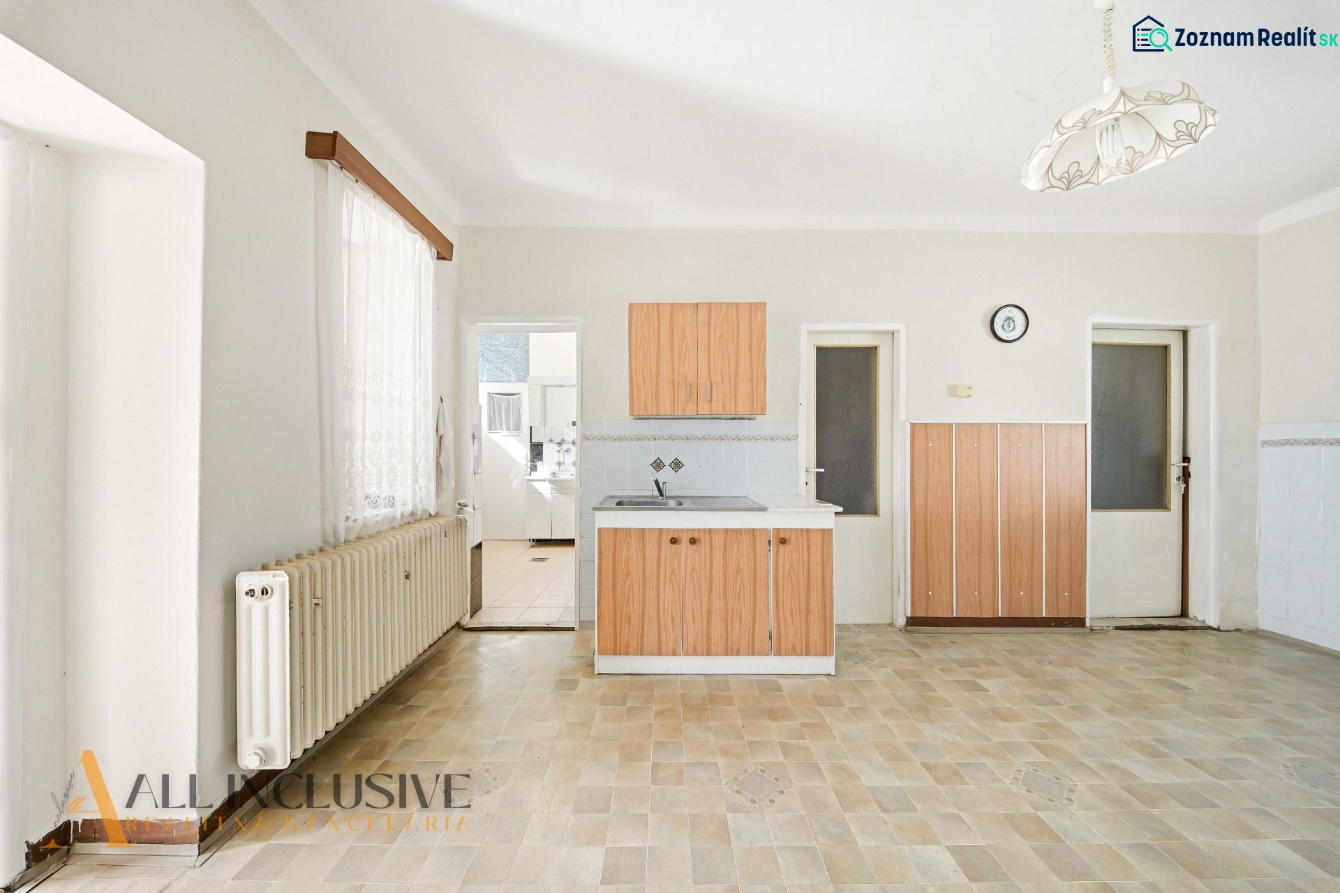 Eine Küche in einem Einfamilienhaus mit einem Boden in Holzoptik und Holzschränken.