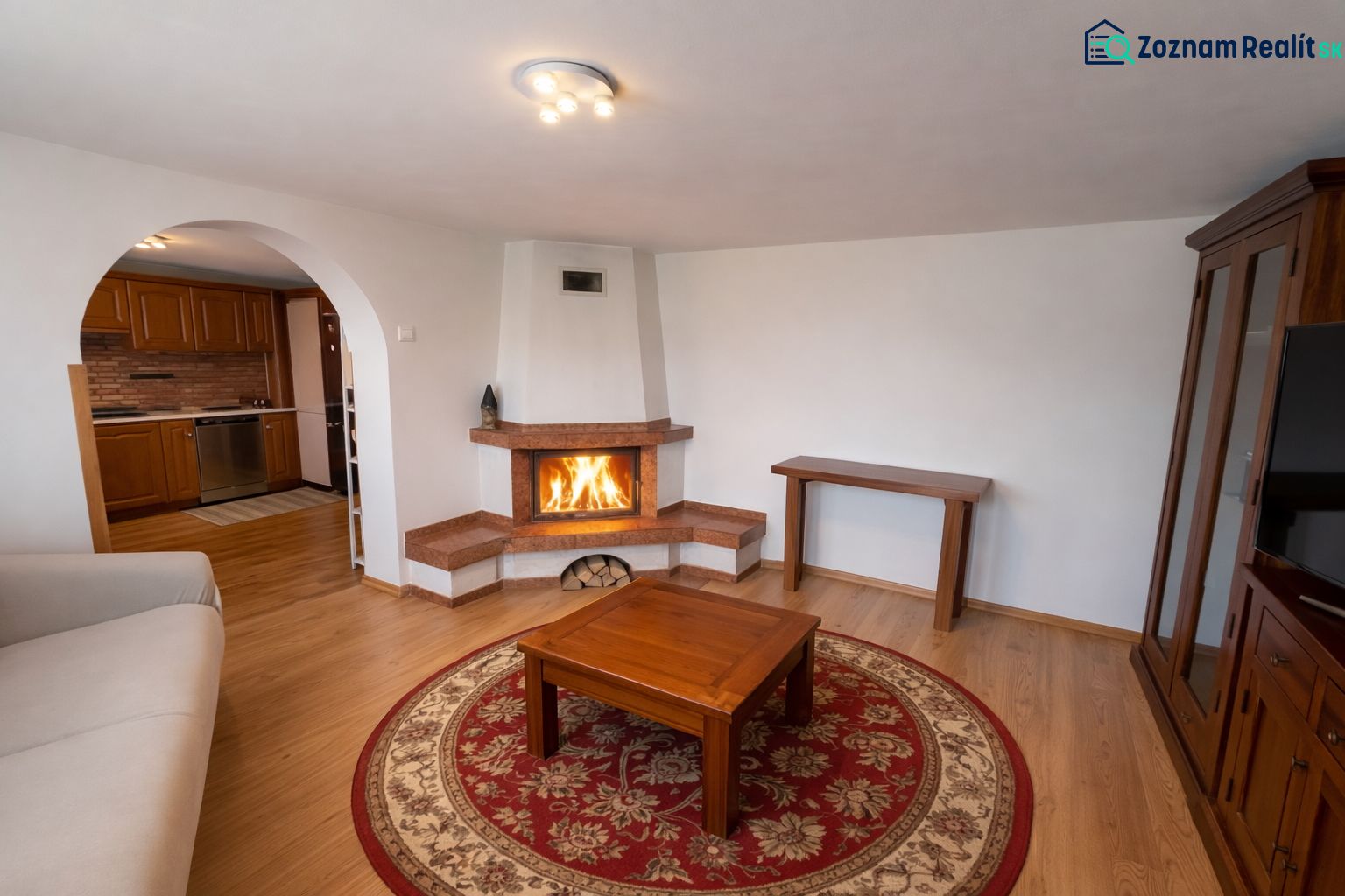 Wohnzimmer in einem Einfamilienhaus mit Kamin, Holzboden und einem bogenförmigen Durchgang.