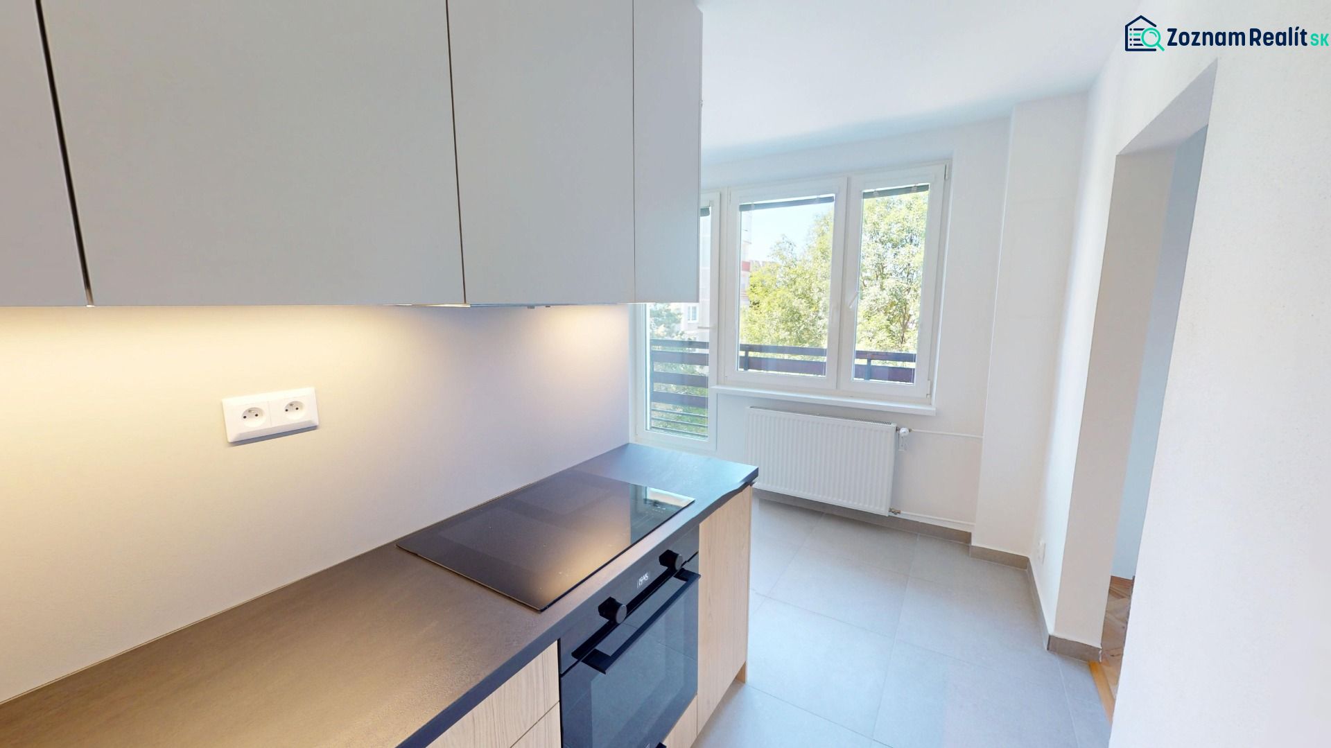Küche in einer 2-Zimmer-Wohnung mit Glaskeramik-Kochfeld und großem Fenster.