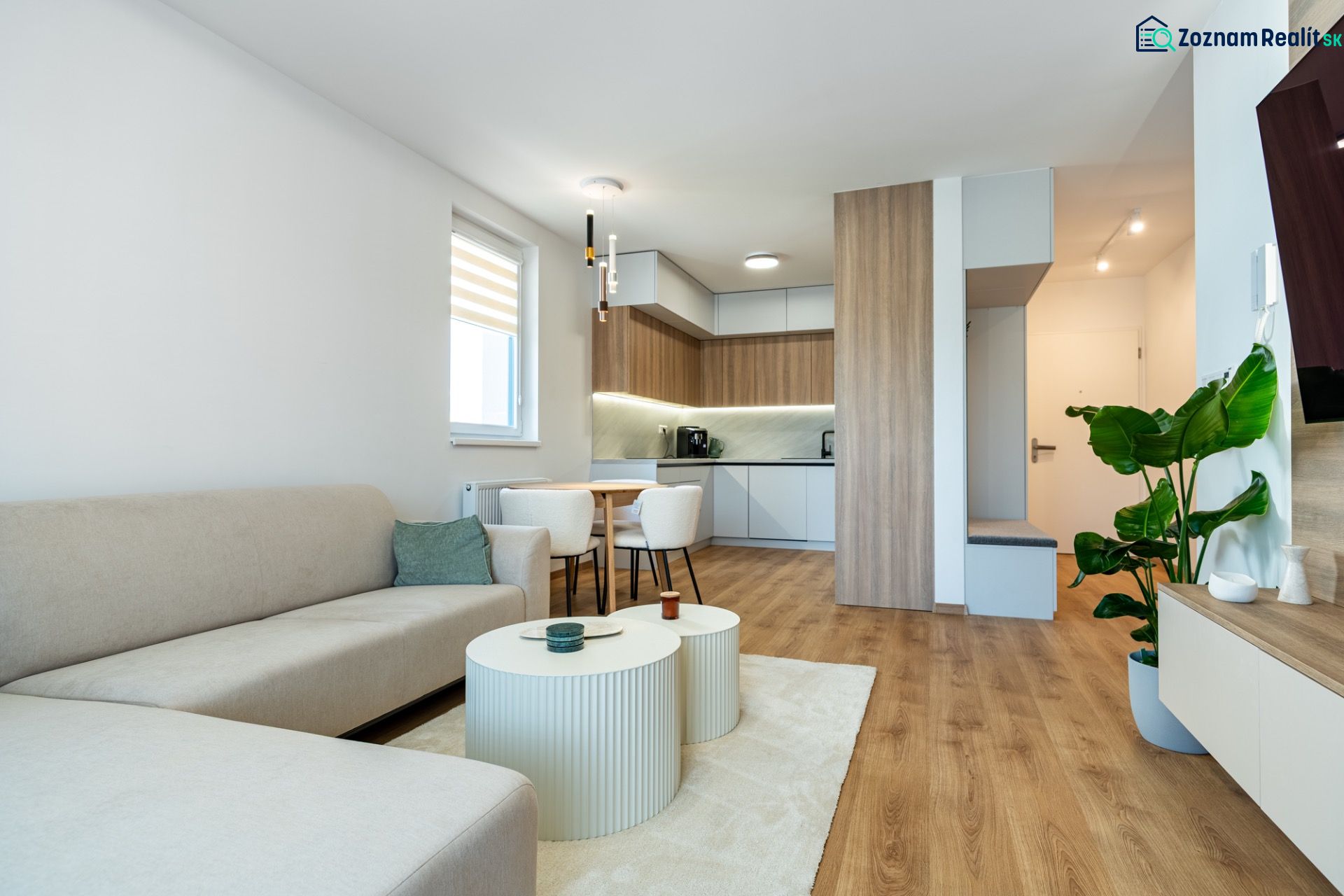Wohnzimmer verbunden mit Küche in einer 3-Zimmer-Wohnung mit Holzboden-Dekor.