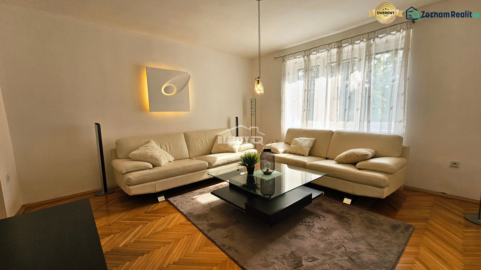Wohnzimmer in einer 2-Zimmer-Wohnung mit weißem Sofa und Boden in Holzoptik.