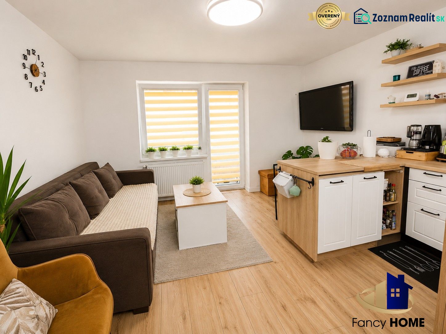Wohnzimmer in einer Zweizimmerwohnung mit Sofa und Küchenzeile, Boden mit Holzdekor.