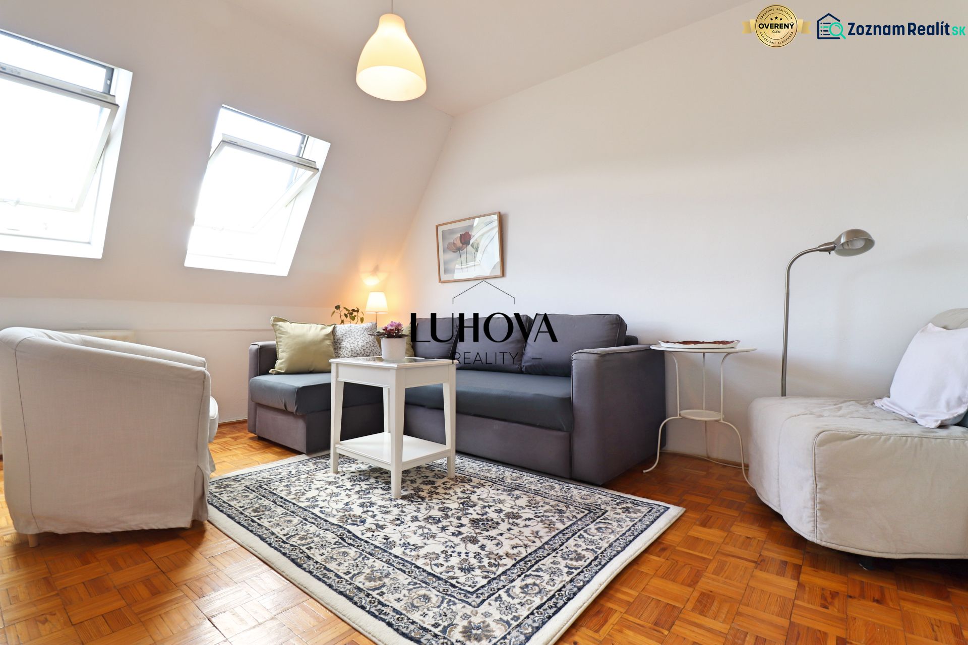 Wohnzimmer in einer 2-Zimmer-Wohnung mit Sofa, Sessel und Teppich, Boden mit Holzdekor.