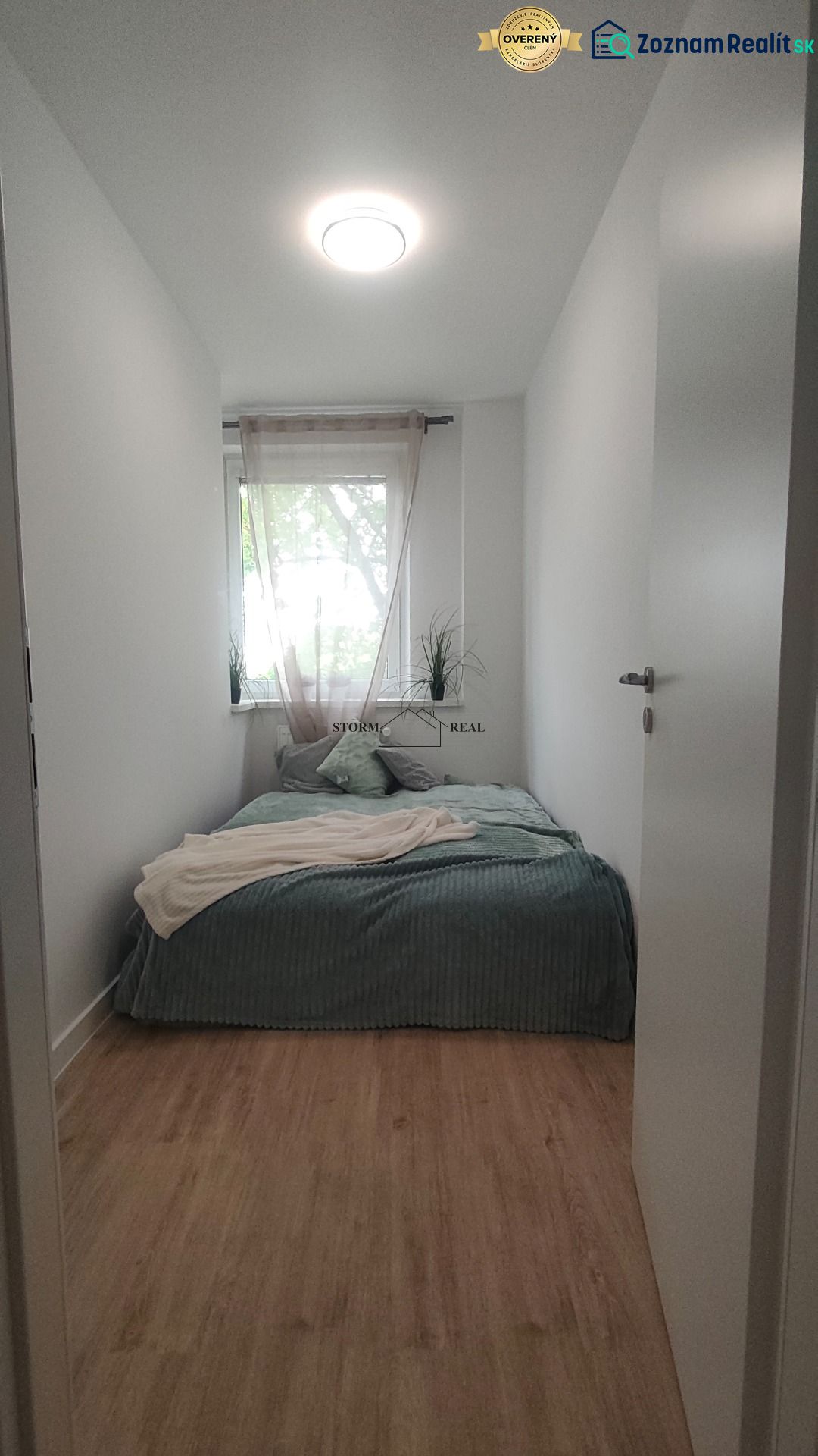 Schlafzimmer mit Bett, weißen Wänden und Boden in Holzoptik in einer 4-Zimmer-Wohnung.