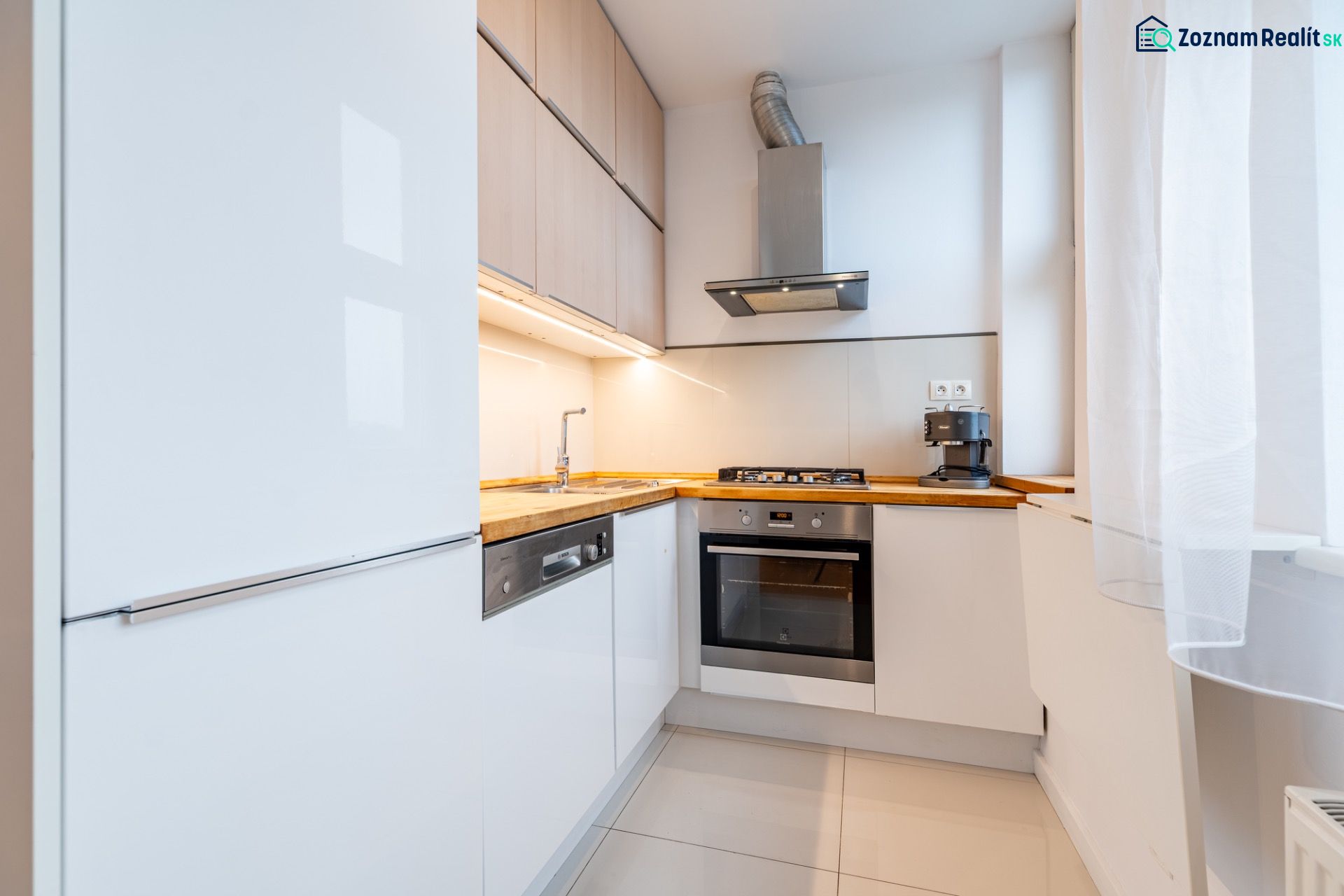 Küche in einer 2-Zimmer-Wohnung mit weißen Schränken und Holzelementen.