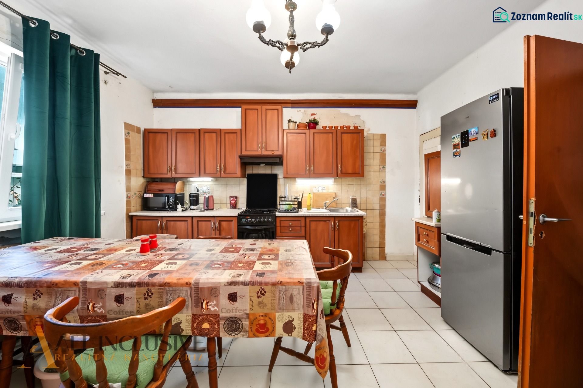Küche in einem Einfamilienhaus mit Esstisch, Holzschränken und Kühlschrank.