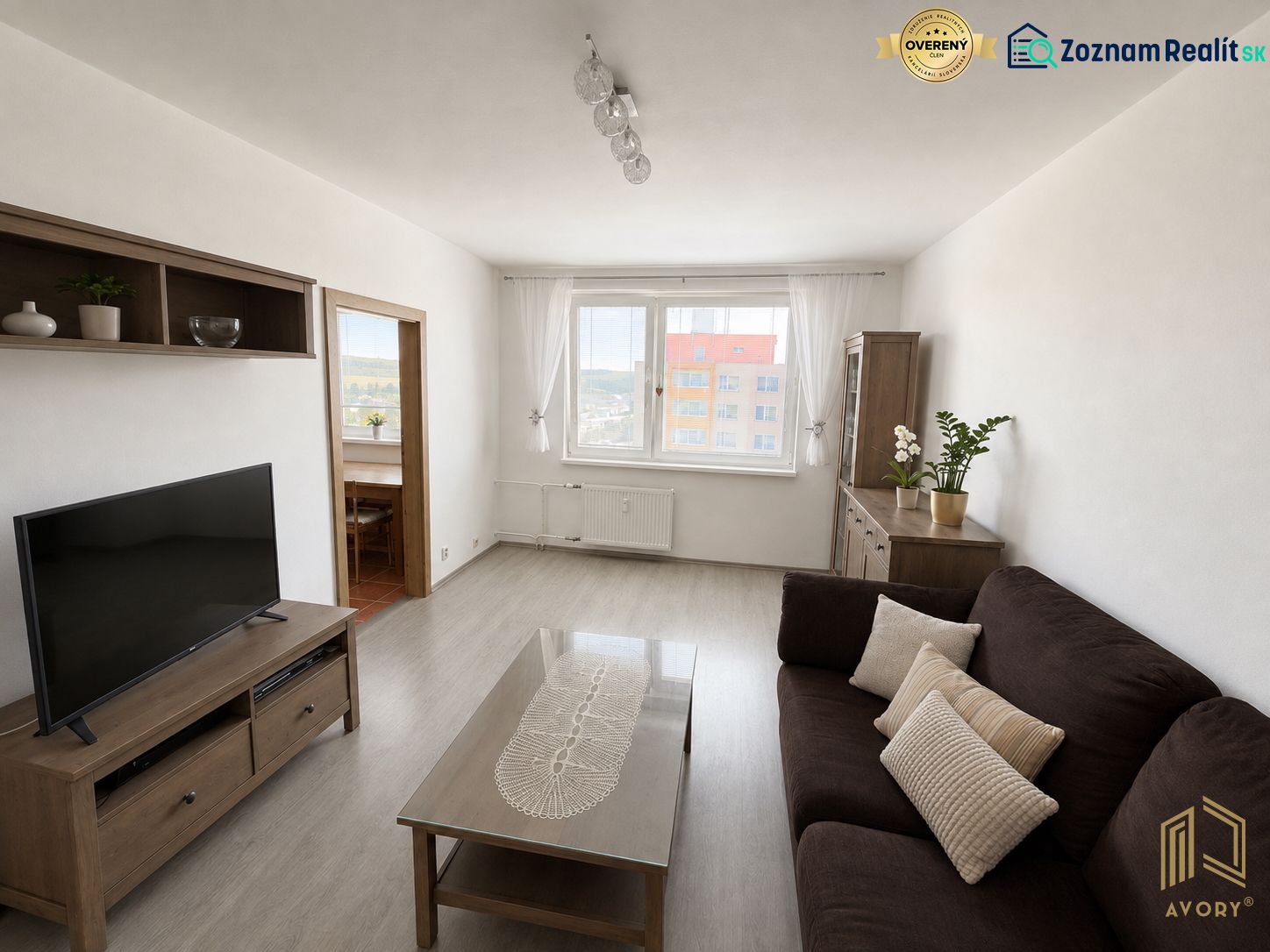 Wohnzimmer in einer 3-Zimmer-Wohnung mit Holzboden und dunklem Sofa.