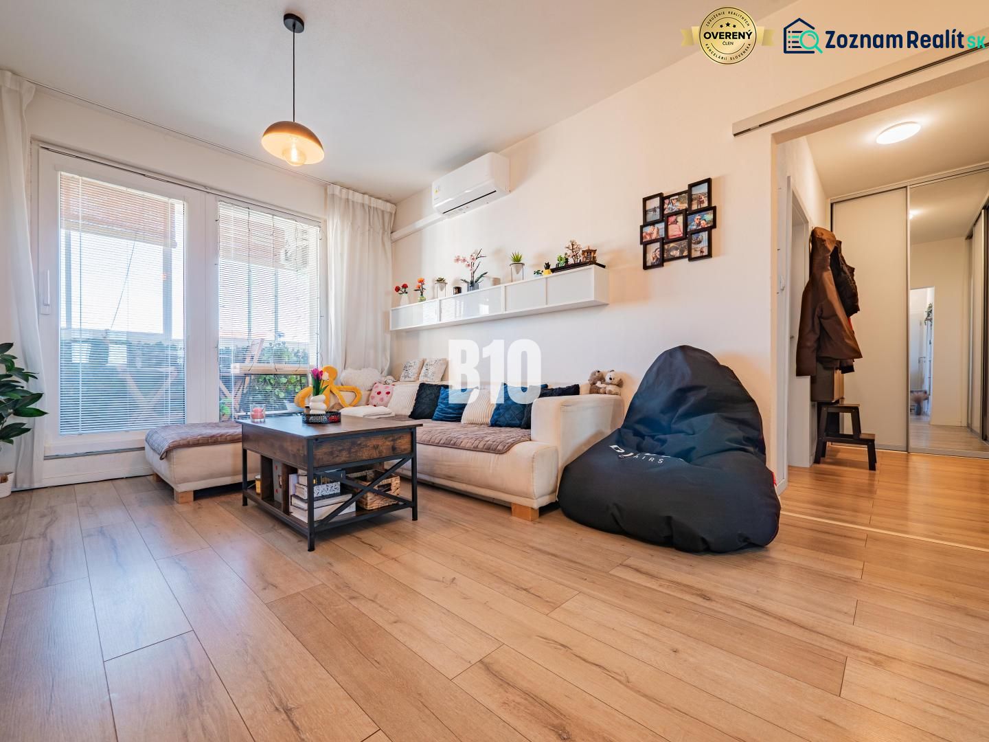 Wohnzimmer in einer 3-Zimmer-Wohnung mit Holzboden, Sofa und großen Fenstern.