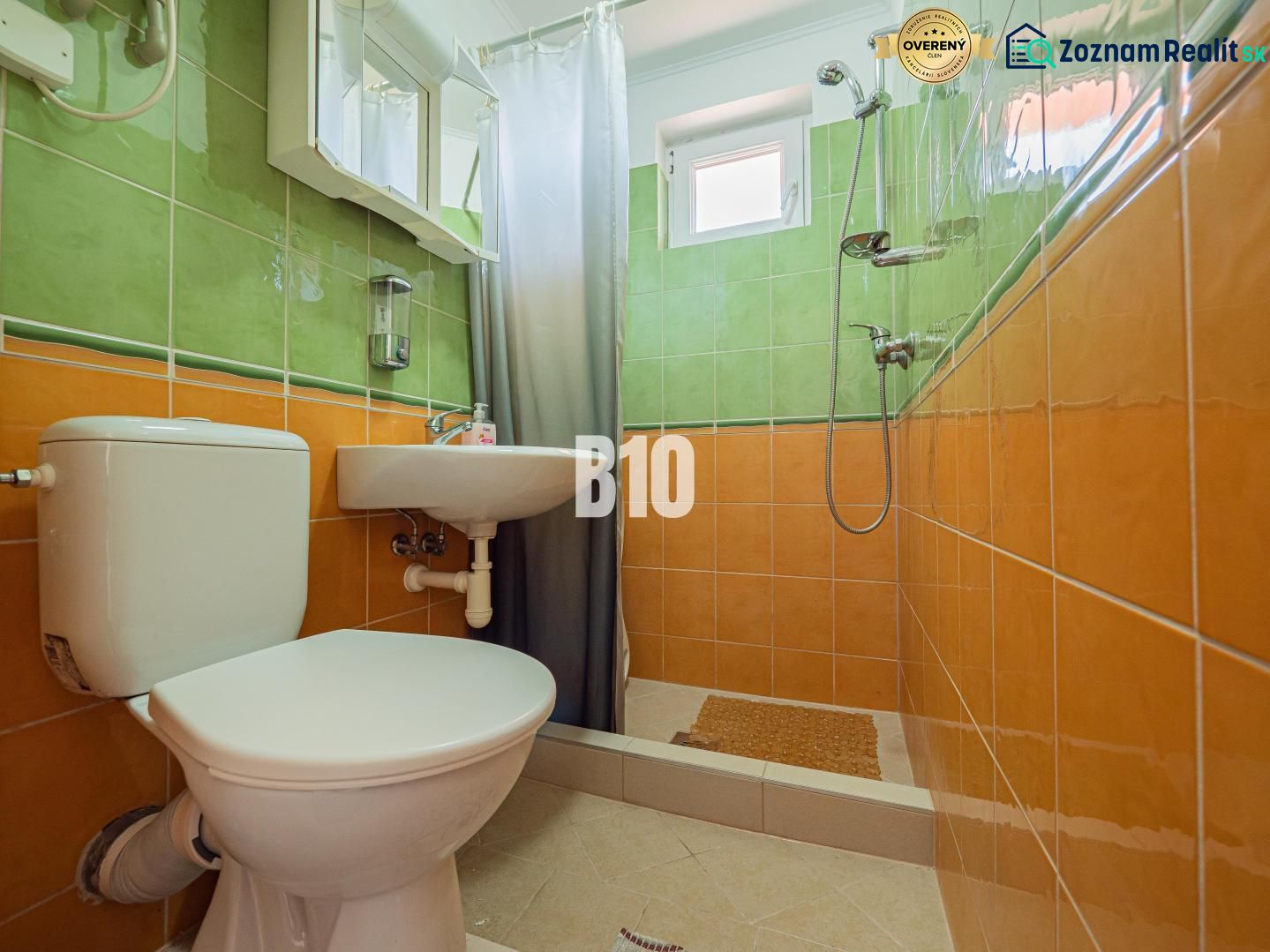 Ein Badezimmer in einem Einfamilienhaus mit orange-grünen Fliesen und einer Duschkabine.