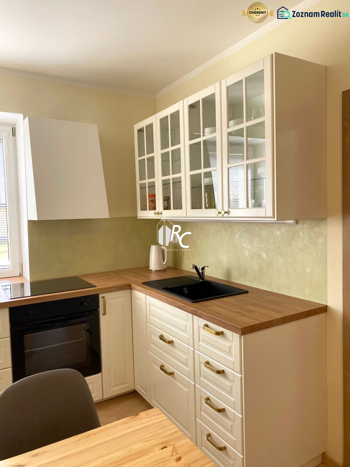 Küche in einer 3-Zimmer-Wohnung mit weißen Schränken und einem Boden in Holzoptik.