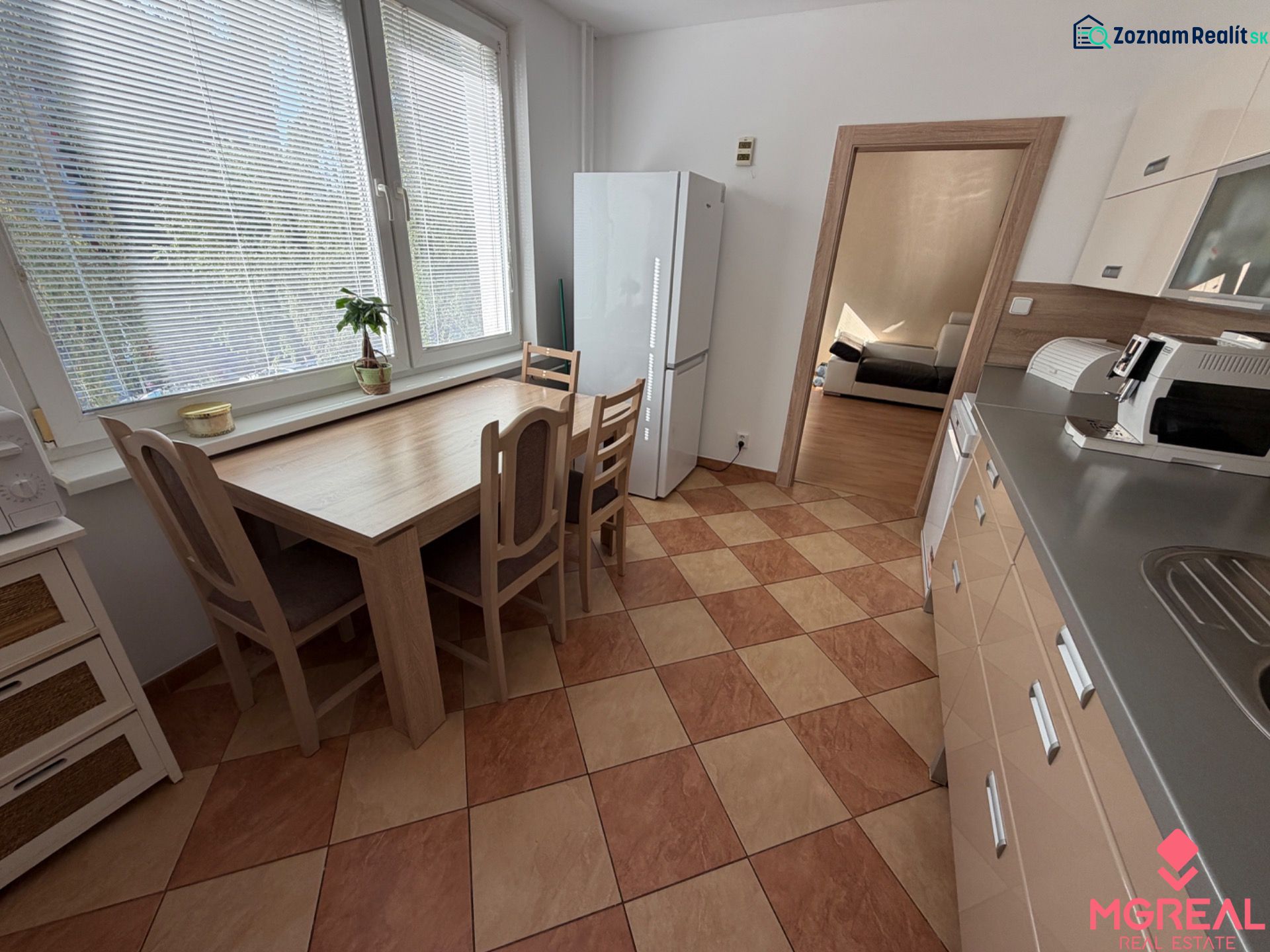 Küche in einer 3-Zimmer-Wohnung mit Fliesenboden, Esstisch und Geräten.