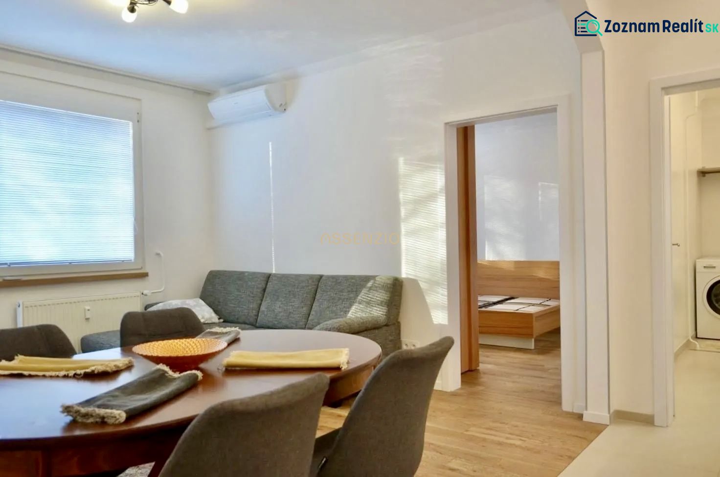 Wohnzimmer in einer 3-Zimmer-Wohnung mit Sofa, Esstisch und Boden in Holzoptik.