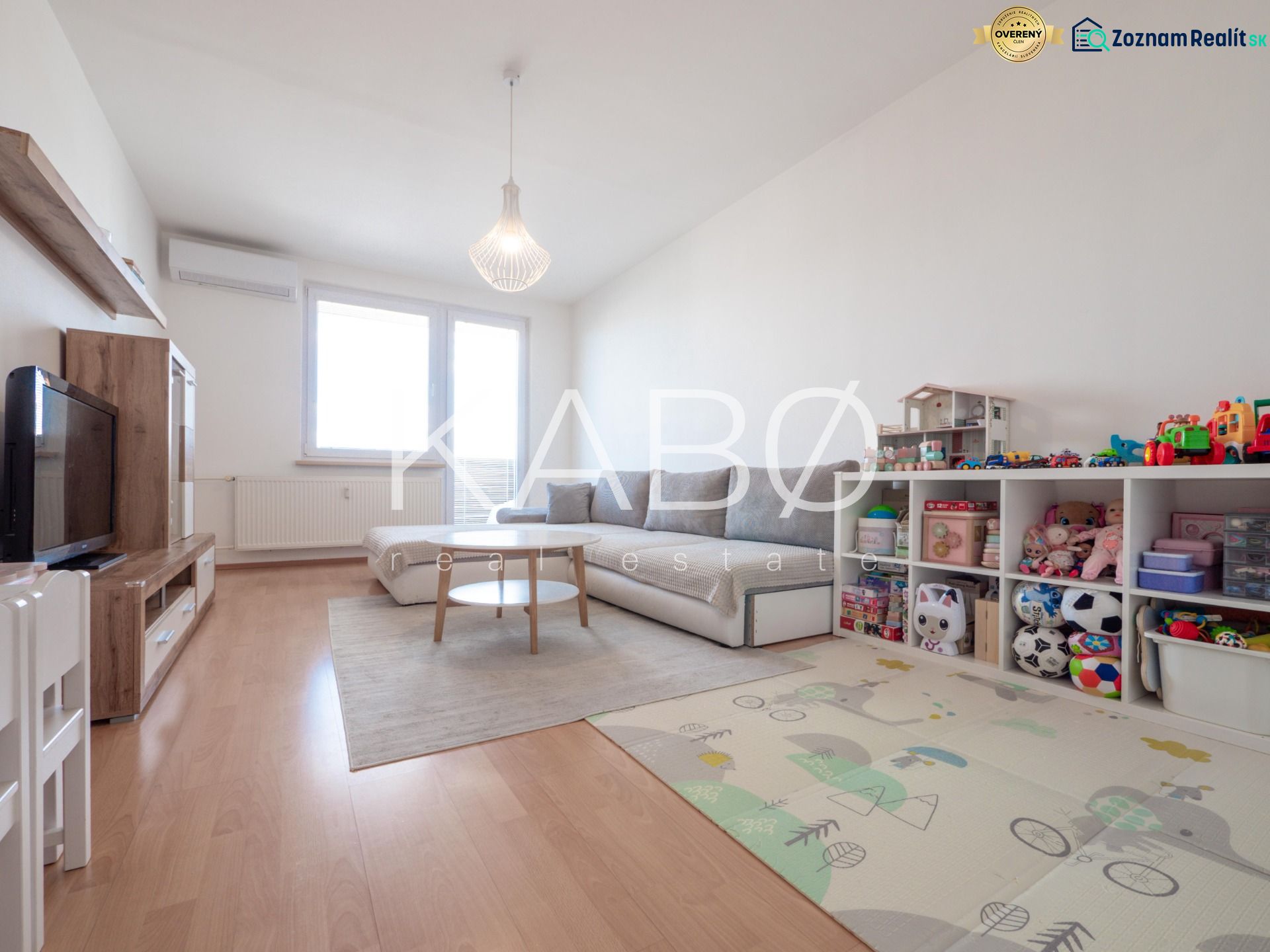 Wohnzimmer in einer Zweizimmerwohnung mit Holzboden und Kinderspielzeug.