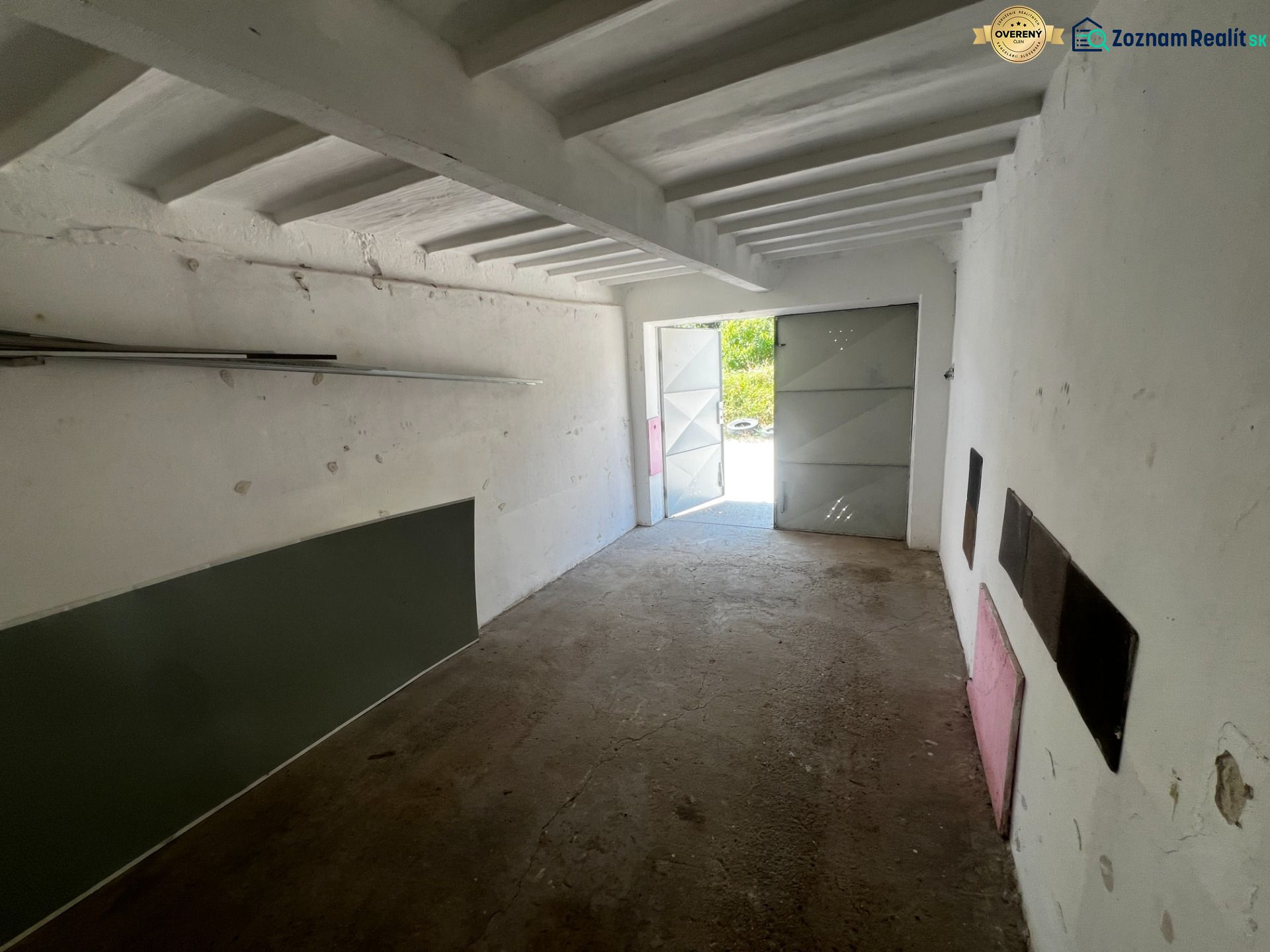 Innenraum einer Garage mit Betonboden und offenen Blechttüren.