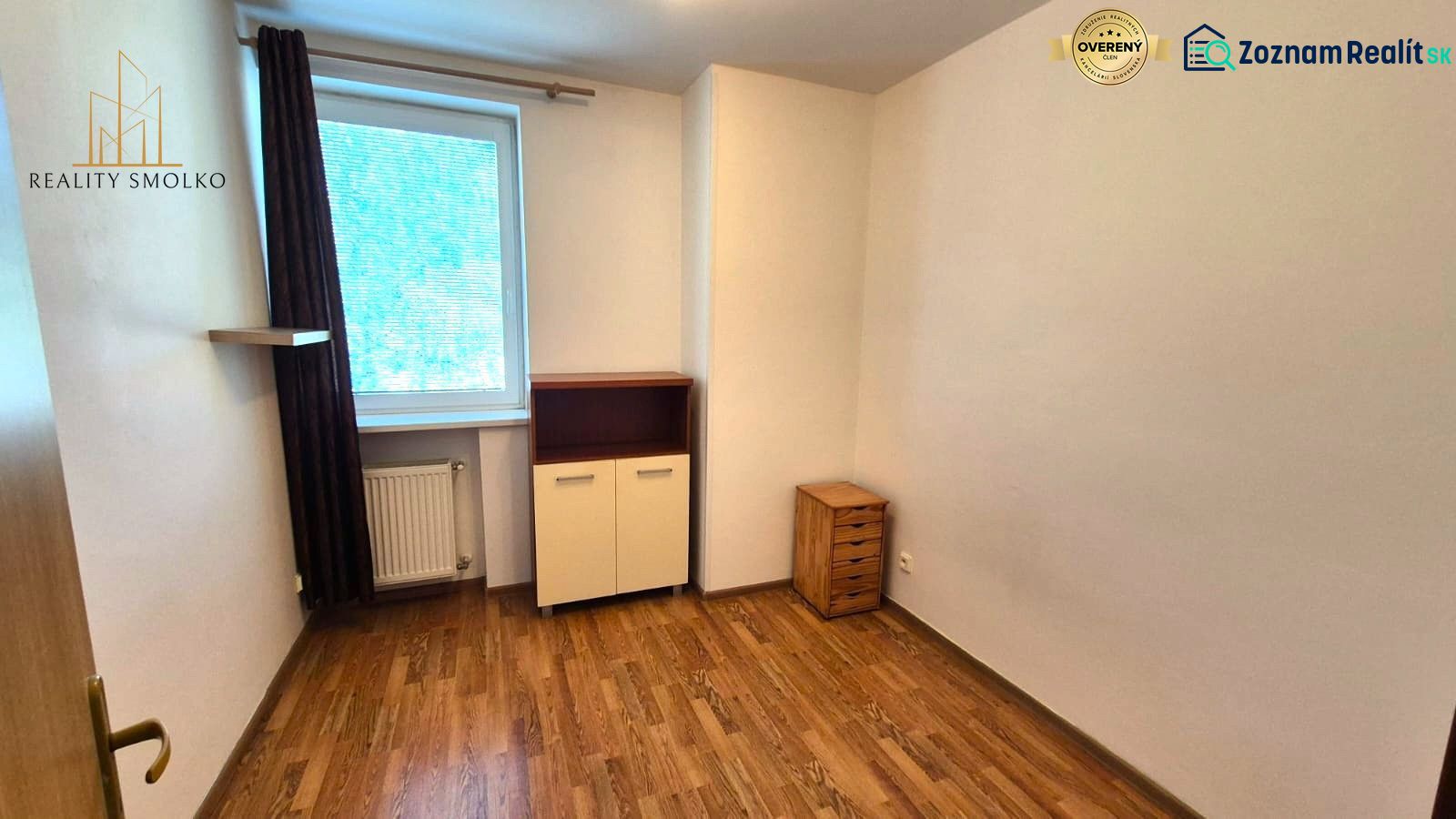 Ein Zimmer mit Holzboden in einer Einzimmerwohnung mit hellen Möbeln.